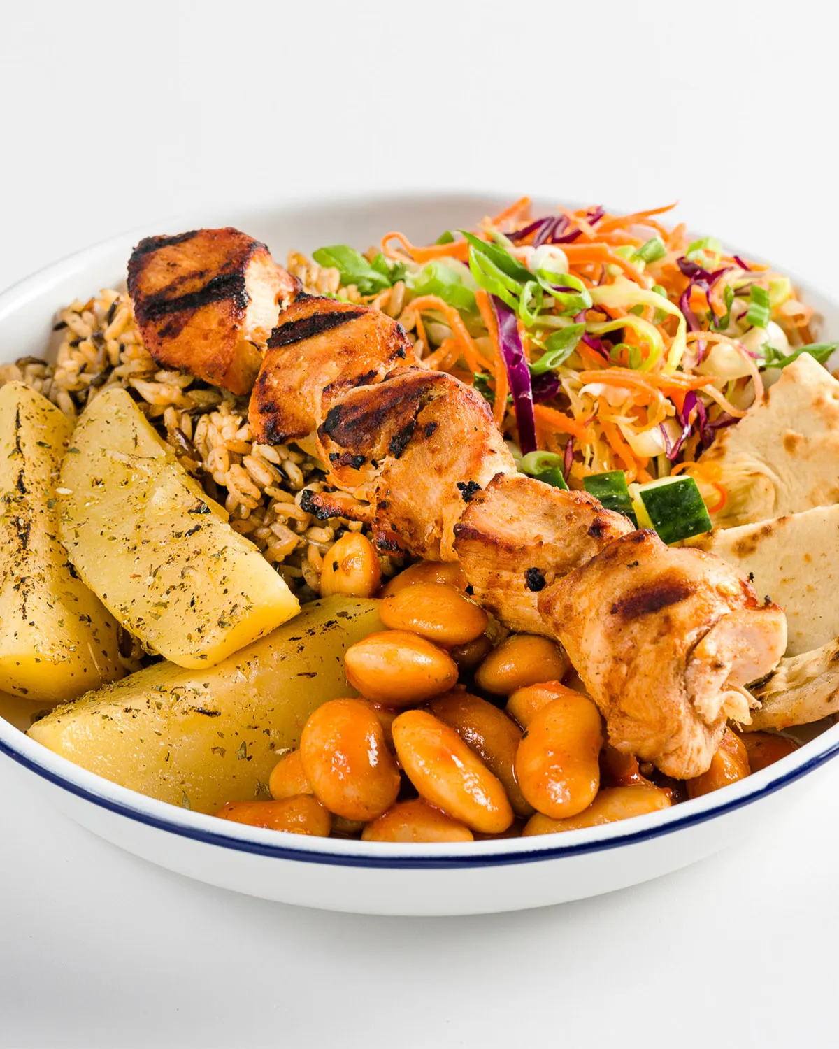 Chicken souvlaki bowl with rice, lemon potatoes, giant beans, slaw and pita