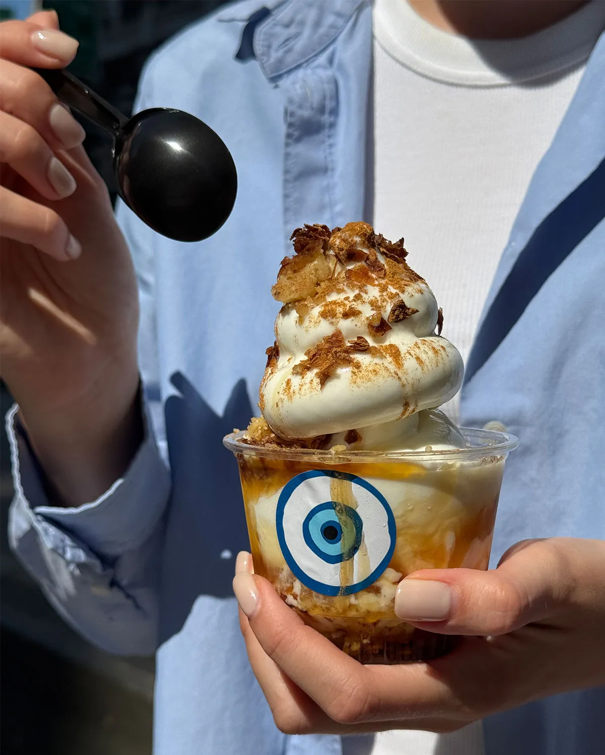 Greek yogurt soft serve with honey and baklava crumble in an evil eye cup