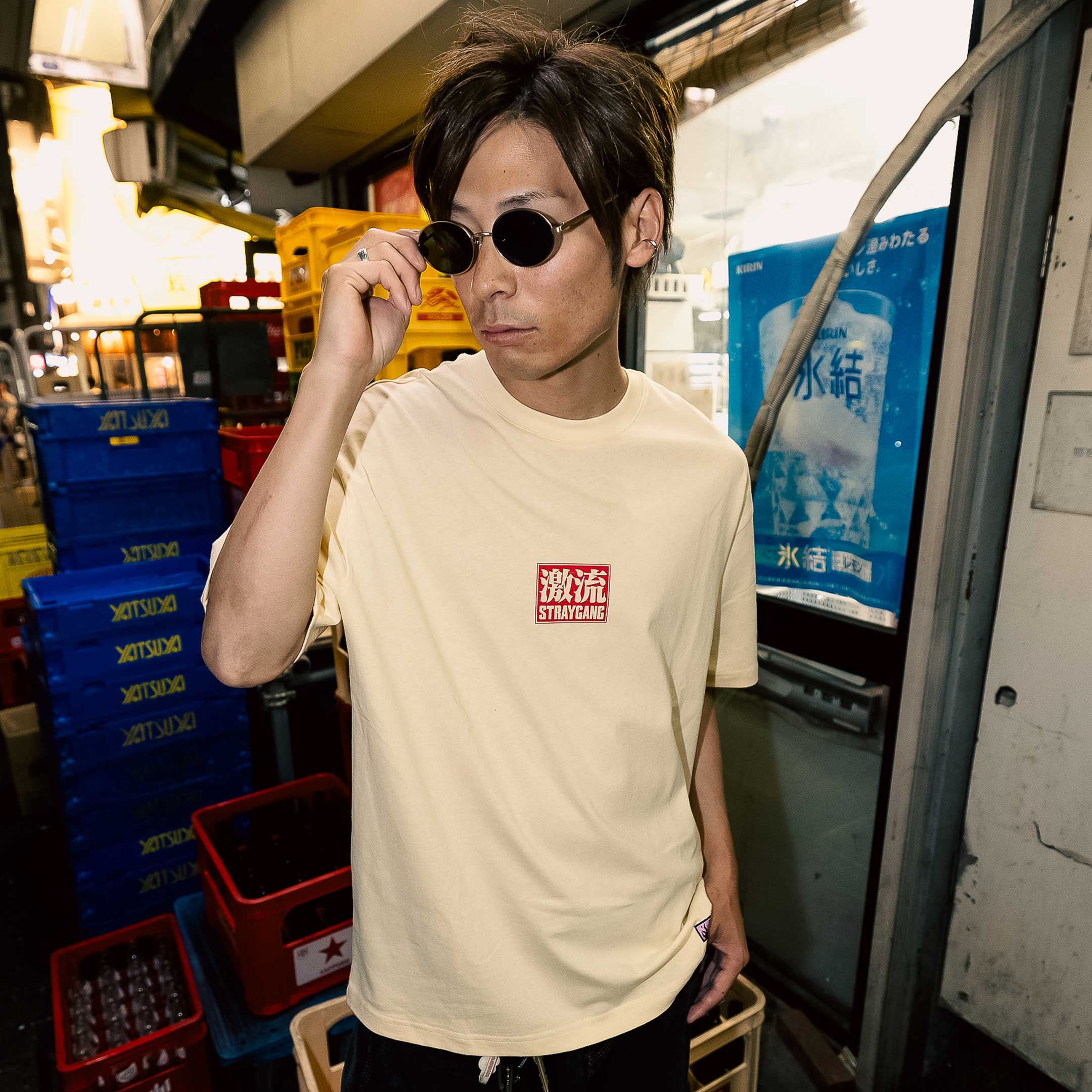 Campaign image of a skater wearing Straygang's cream supernova tee on the streets of Tokyo. The front design, says 'Straygang' with some Japanese kanji, adding some contrast to the backdrop.