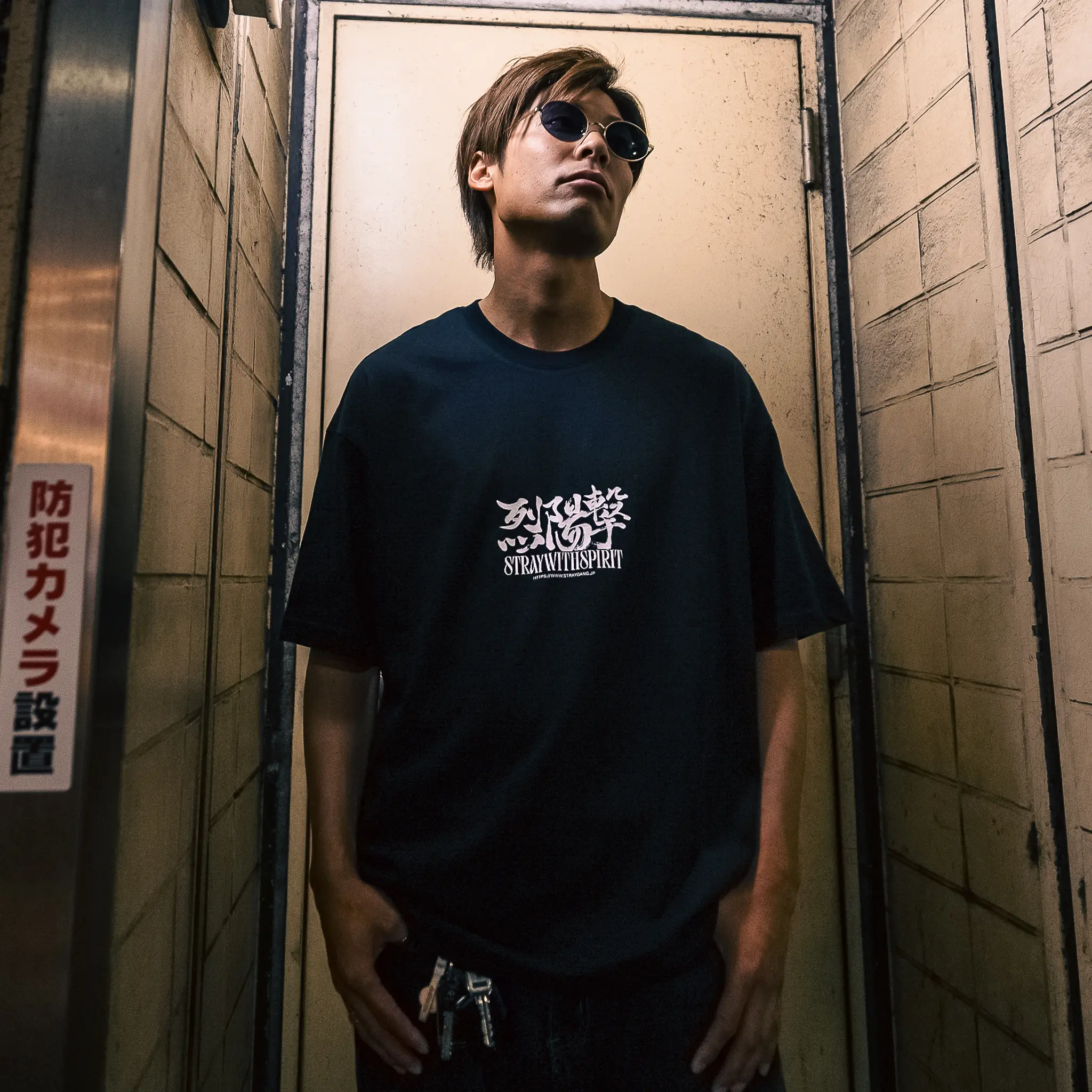 Campaign image of a skater wearing the black strike tee on the streets of Tokyo. The front design, perfectly meshes english and Japanese kanji together for an impactful print.