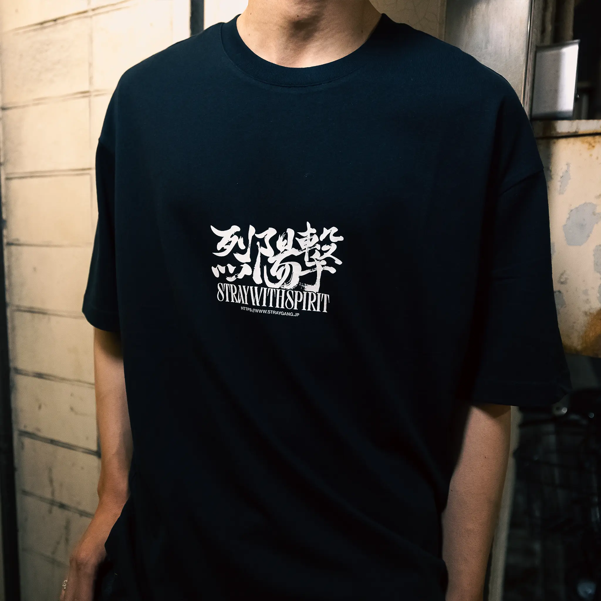 Image that shows a closer look of the strike tee's print, worn amidst the back-alleys of Tokyo by a local skateboarder. 
