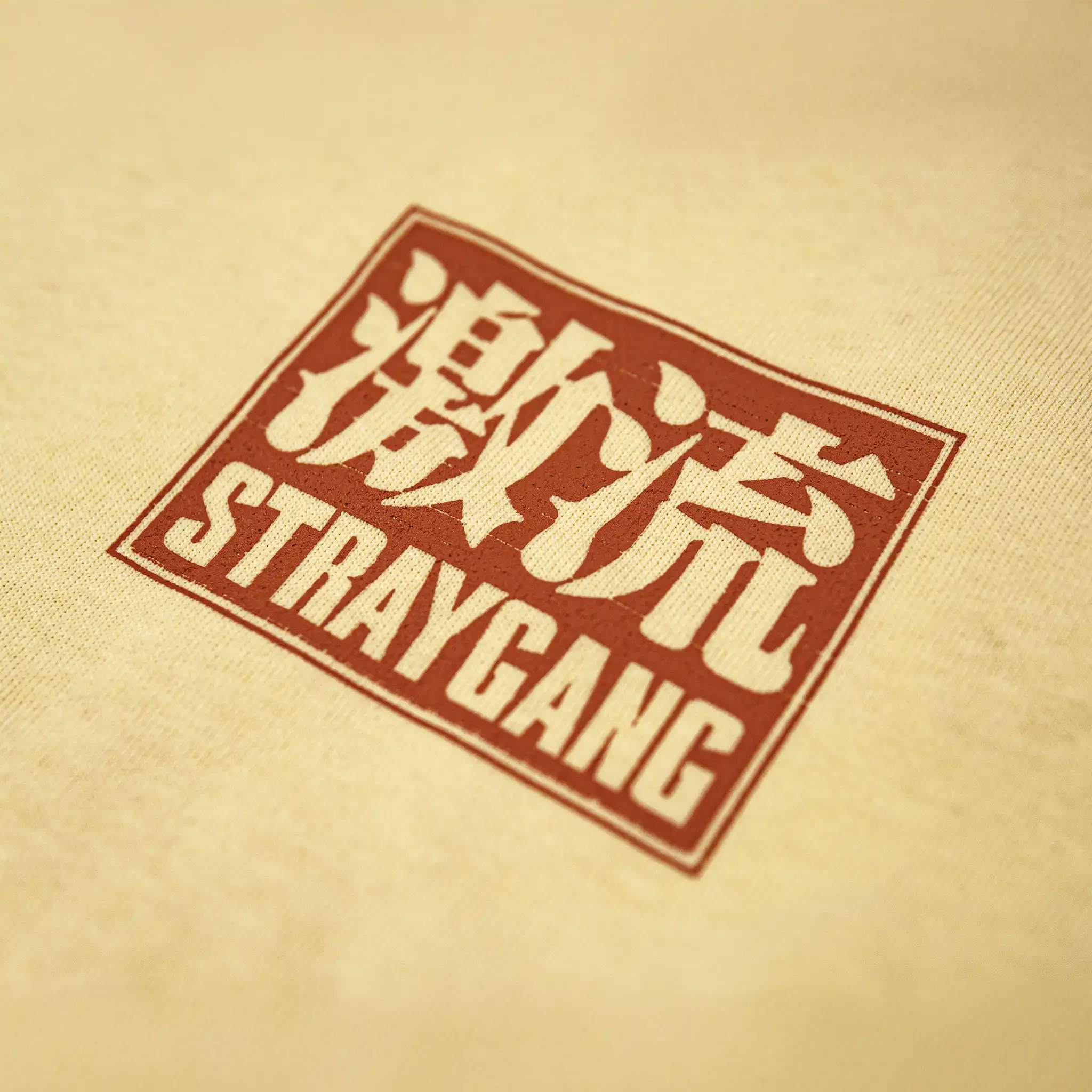 Close-up of Straygang Supernova Tee chest print, red kanji ‘激流’ with Straygang text logo on cream cotton fabric.