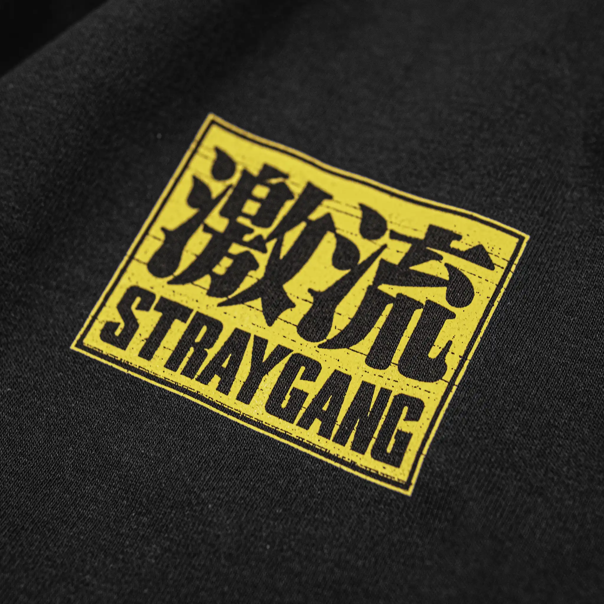 Close-up of the Straygang Supernova Tee front chest graphic in yellow, showing 激流 kanji and Straygang text with cracked print texture.
