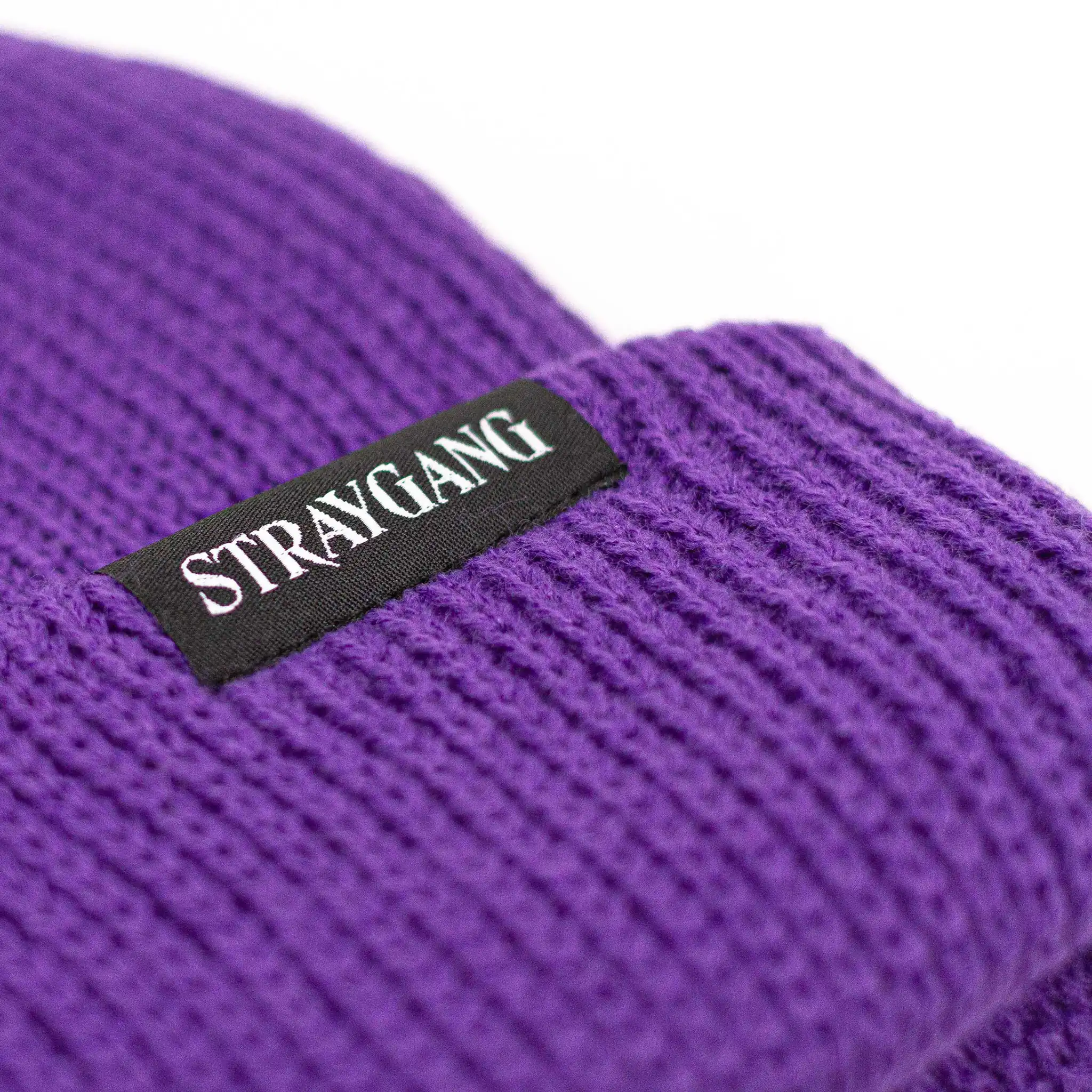 Close-up image highlighting the back of Straygang's 'SWS' purple beanie, showing the branded woven label in detail. This shot focuses on the outside of the label that has 'Straygang' written on it.