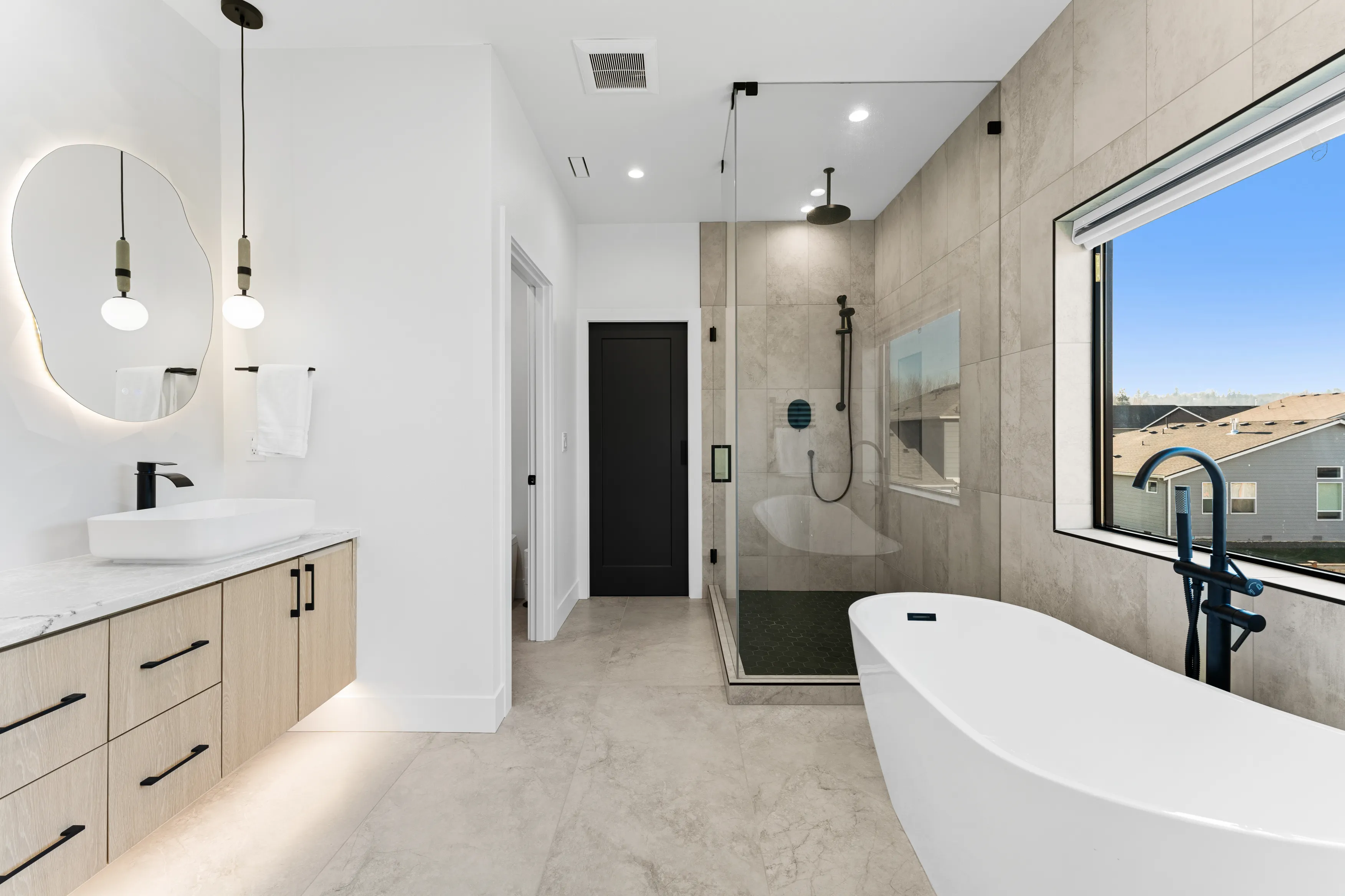 Fully custom modern kitchen in Issaquah with black and wood cabinetry, large island, pendant lighting, and open layout.