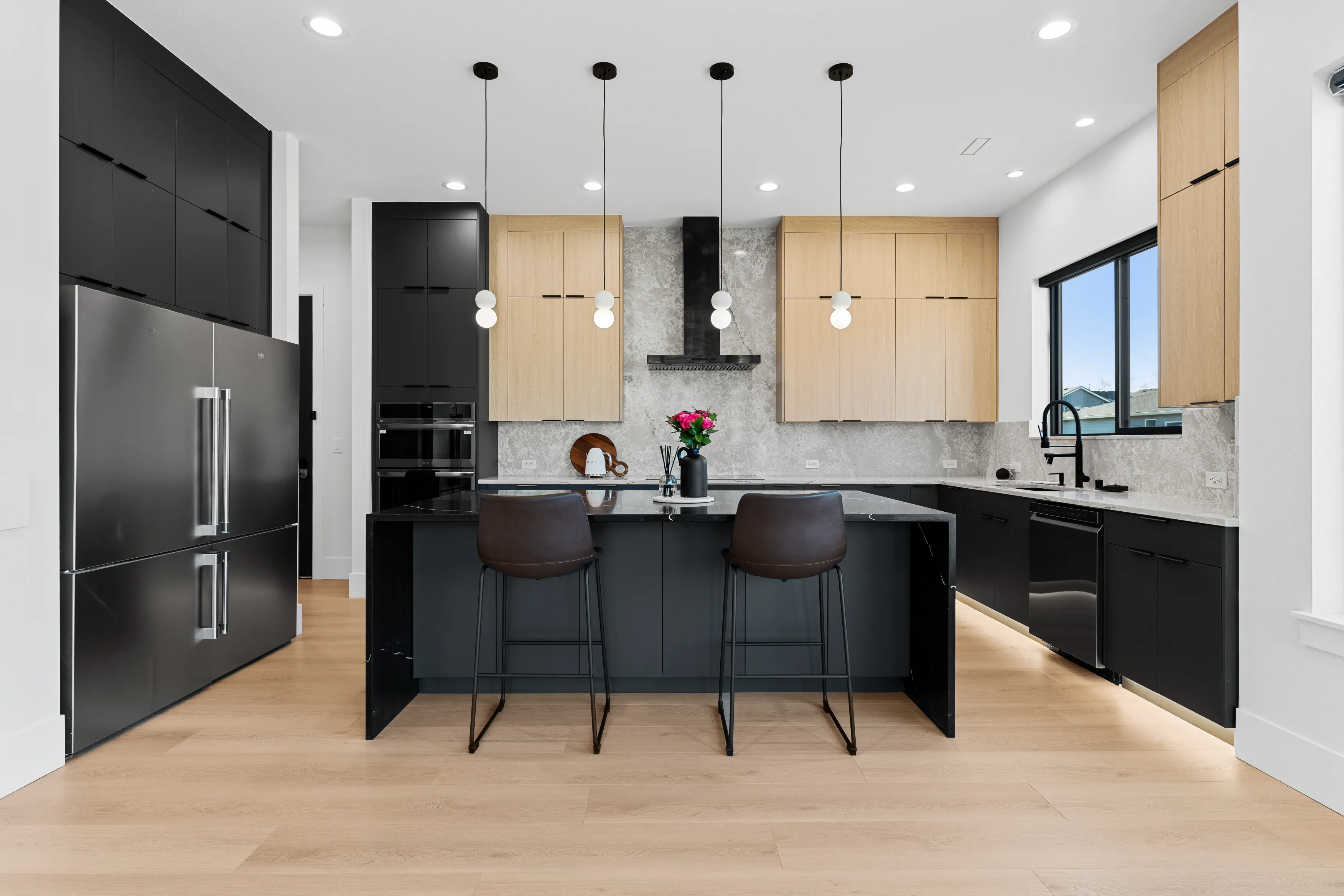 Modern custom kitchen design in Issaquah featuring a black island, wood cabinets, built-in appliances, and clean lines.