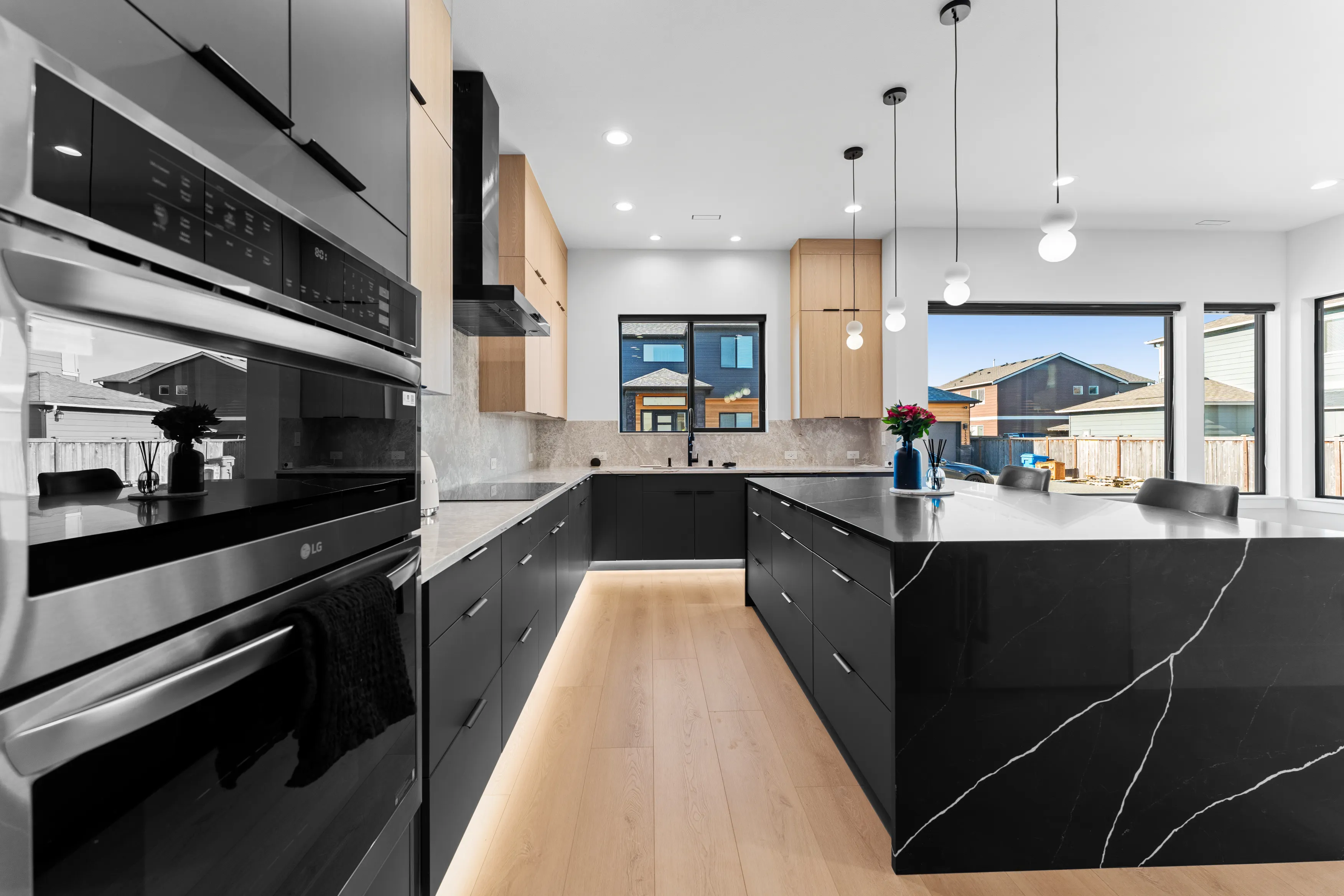 Fully custom modern kitchen in Issaquah with black and wood cabinetry, large island, pendant lighting, and open layout.