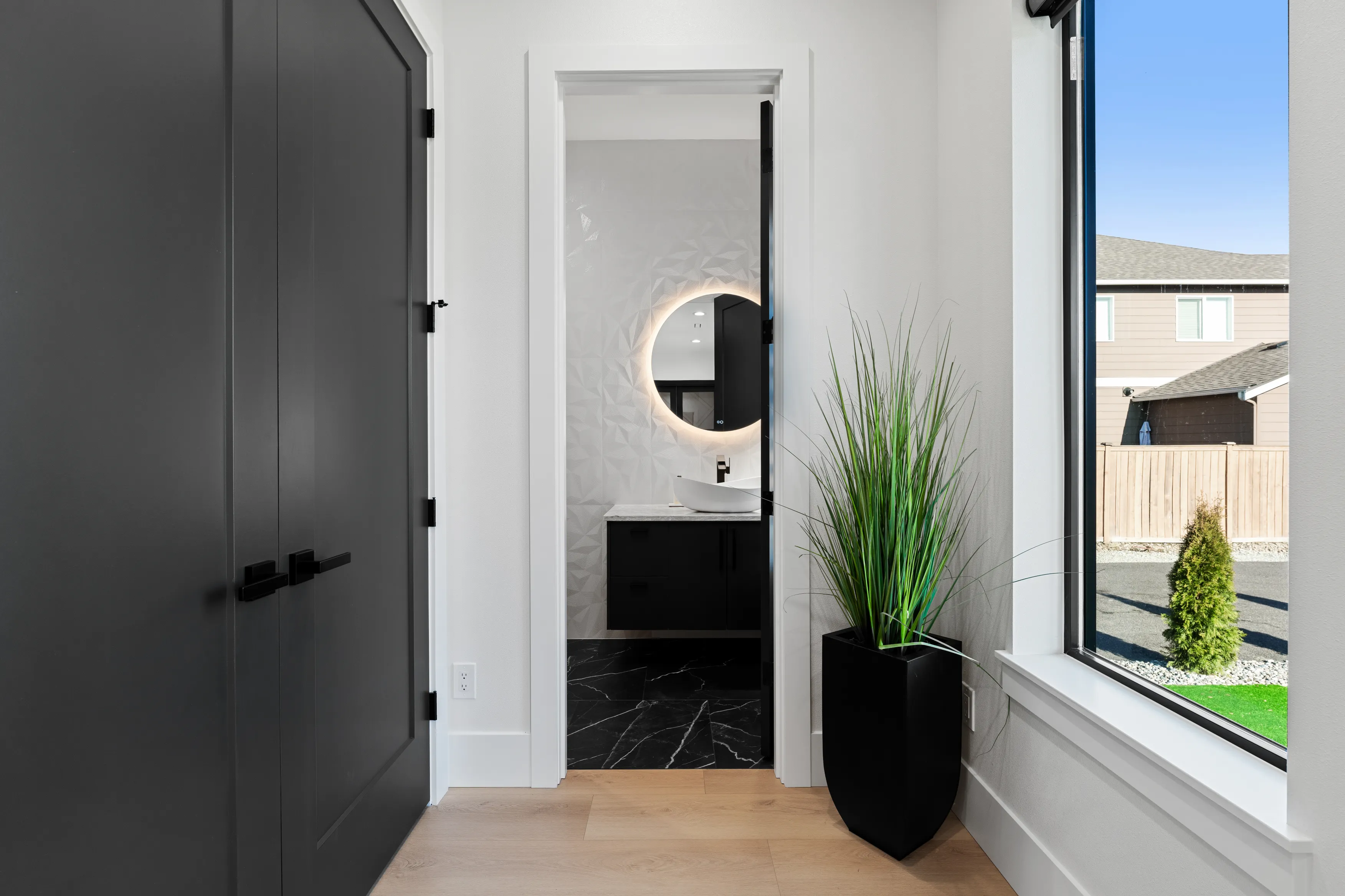 Custom home living space in Issaquah with light hardwood floors, curved staircase railing, and modern open-plan layout.