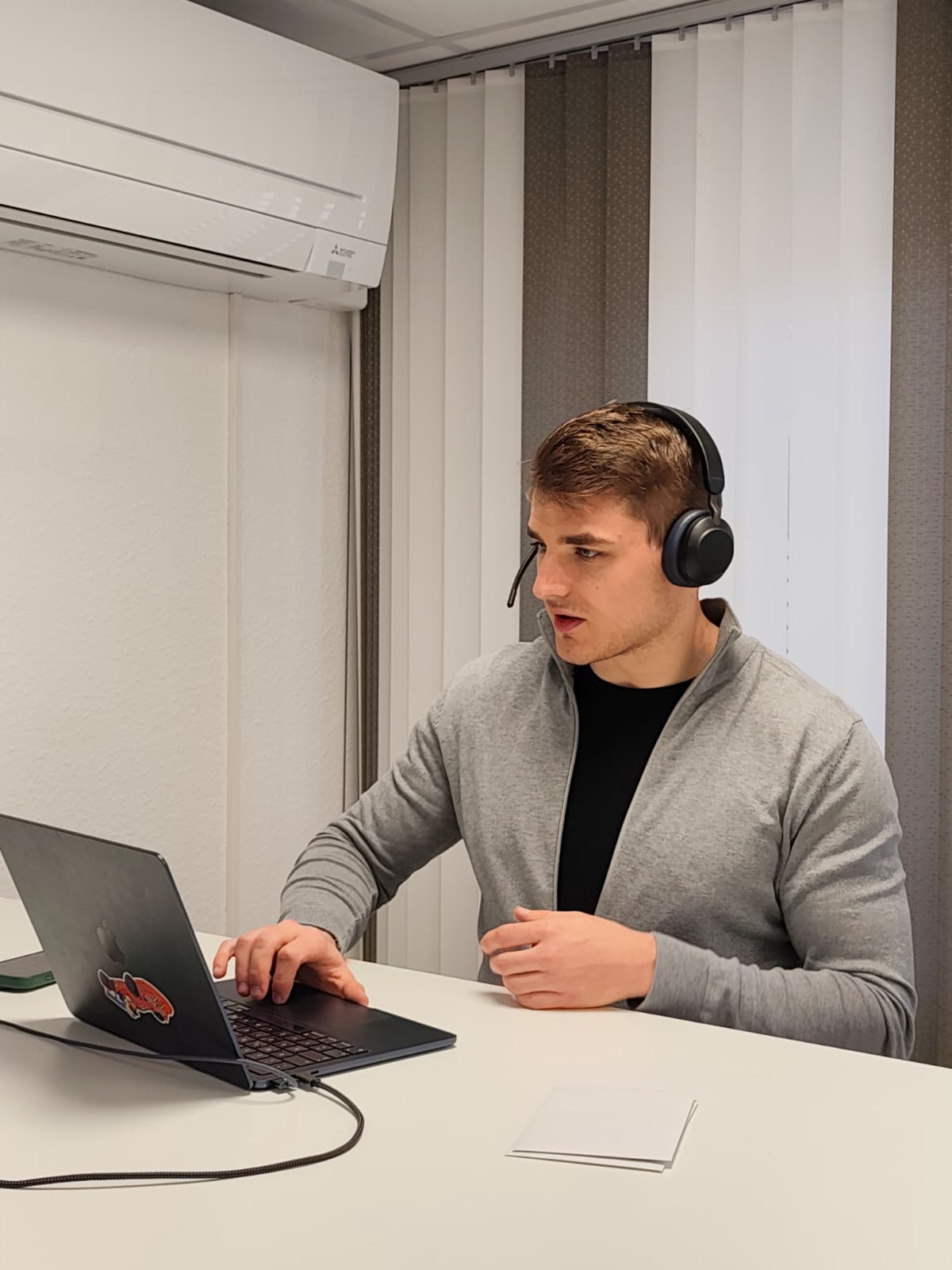 Mann mit Headset arbeitet an einem Laptop in einem Büro mit Klimaanlage