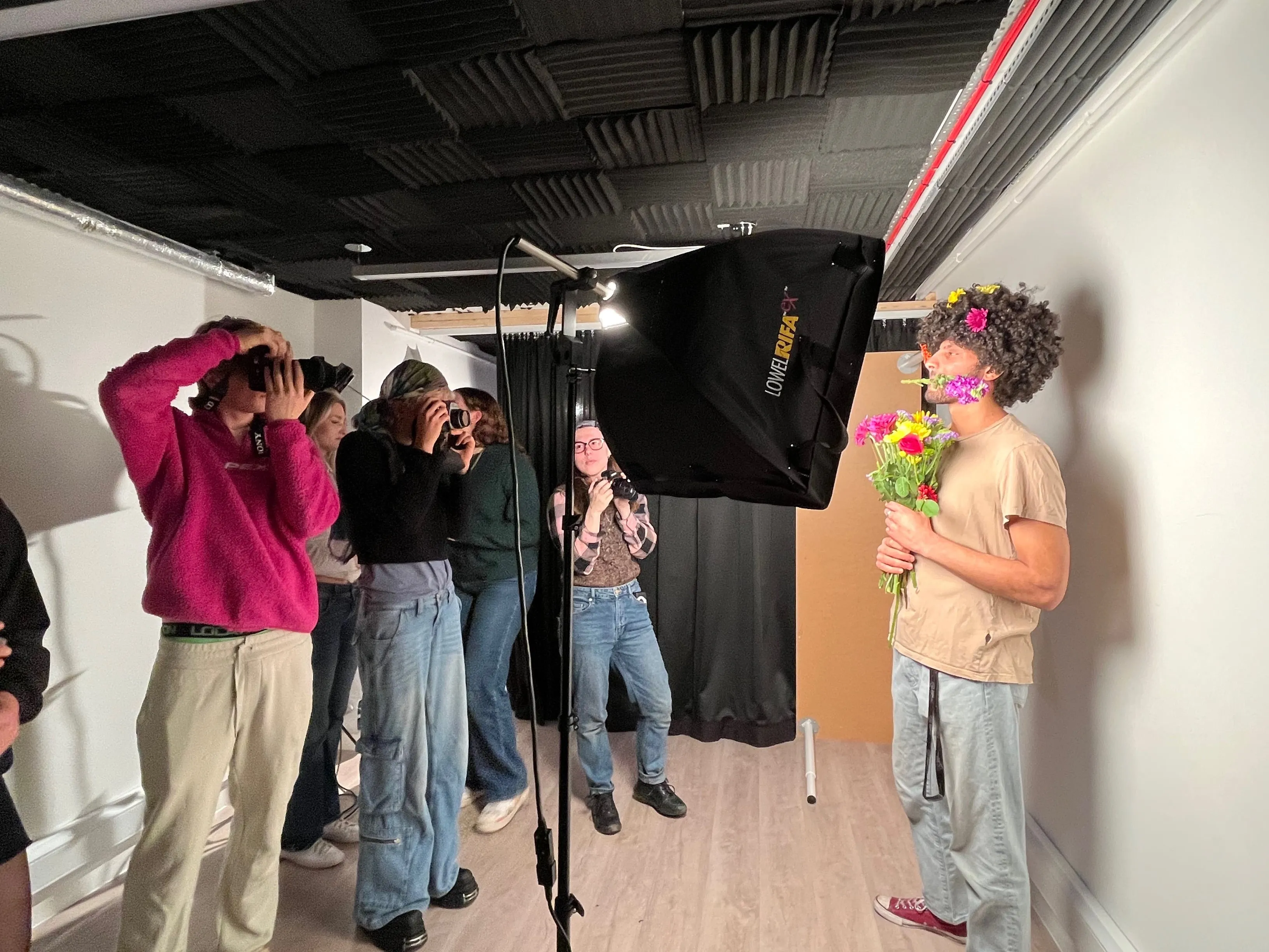 Several people taking a photo of a man with some flowers