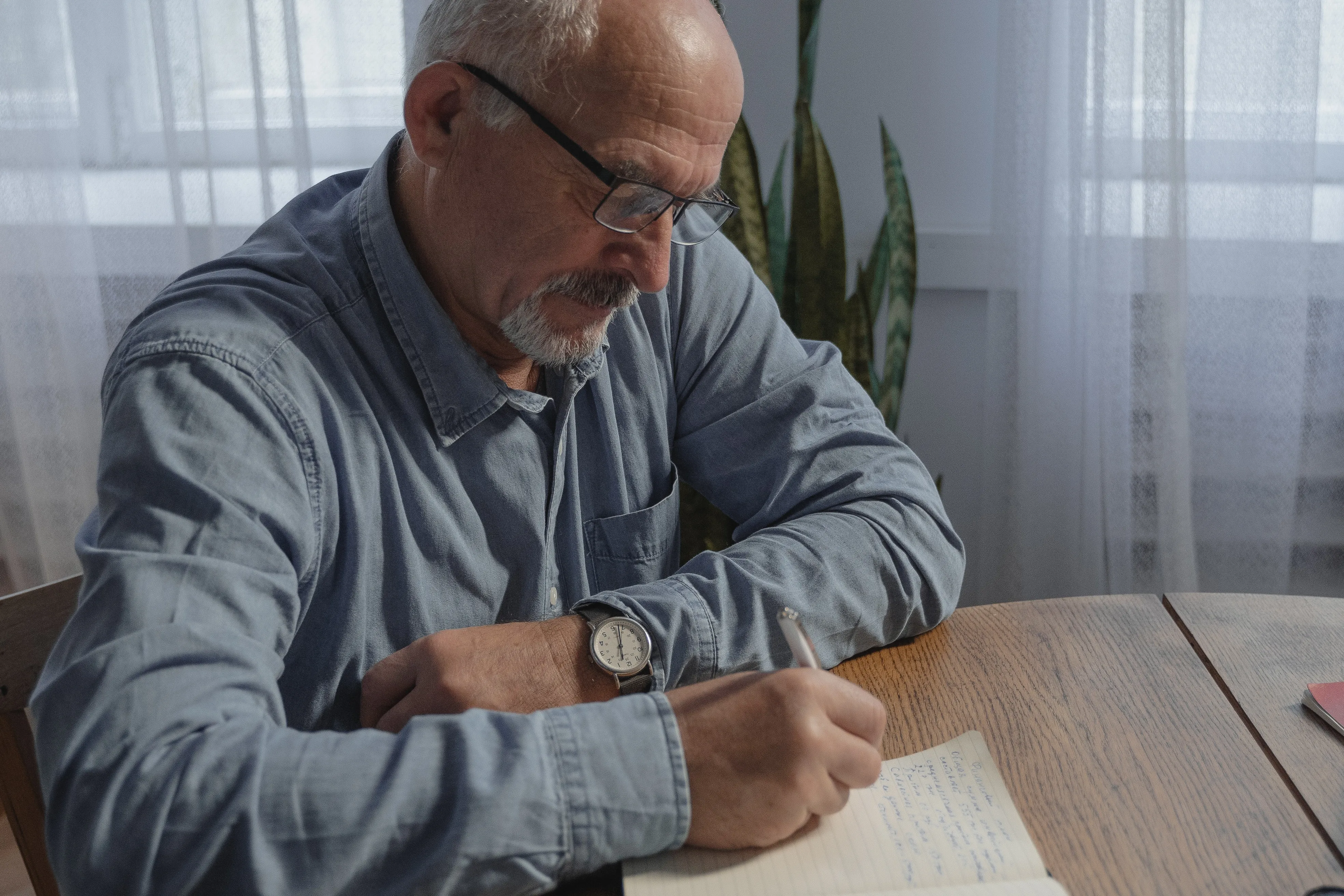 A retiree writing notes in his journal. 