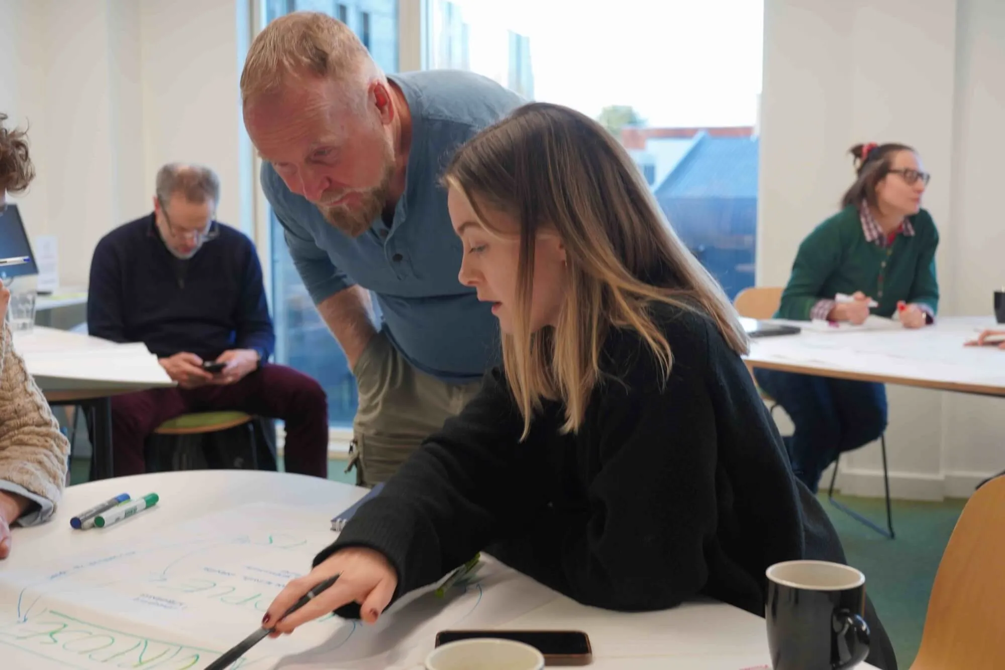 A LIS MBA mentor guides a student during a strategy mapping exercise in a light-filled seminar room.