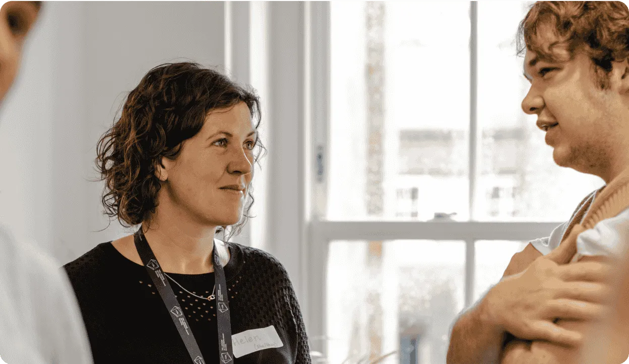 Woman smiling and talking with a man, both engaged in conversation.