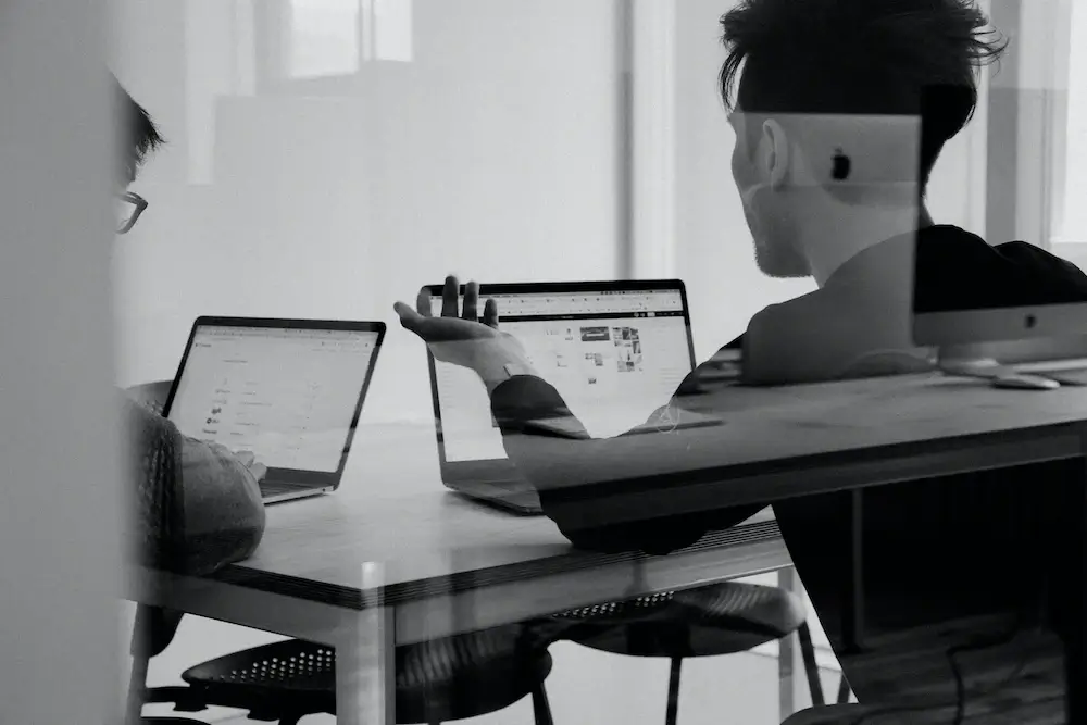 Two men in front of their laptops on a table 