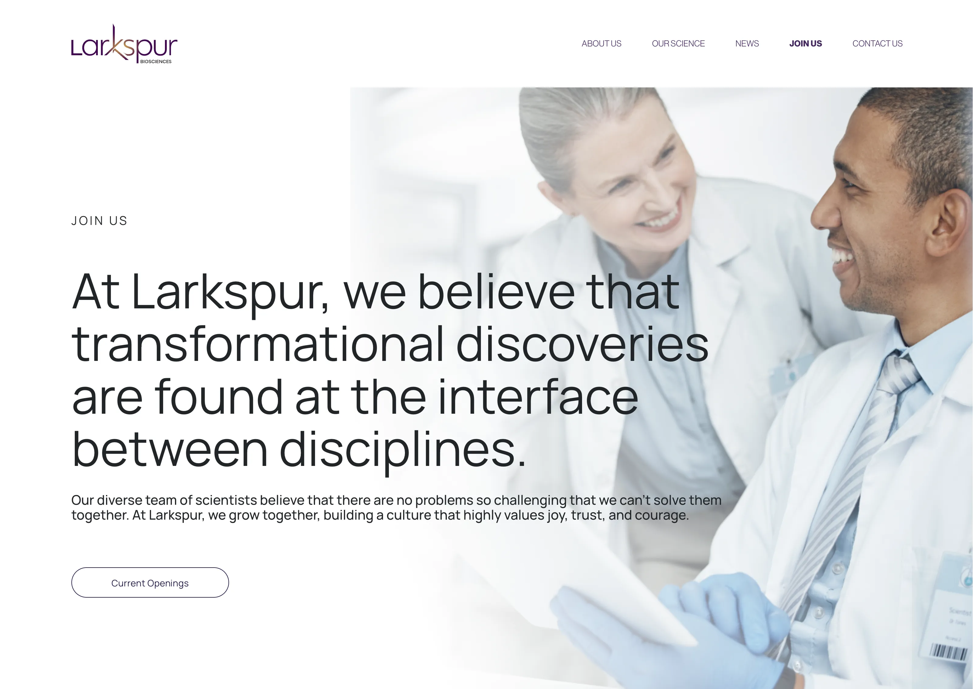 Two smiling scientists in white lab coats looking at a tablet, promoting collaboration and innovation at Larkspur Biosciences.