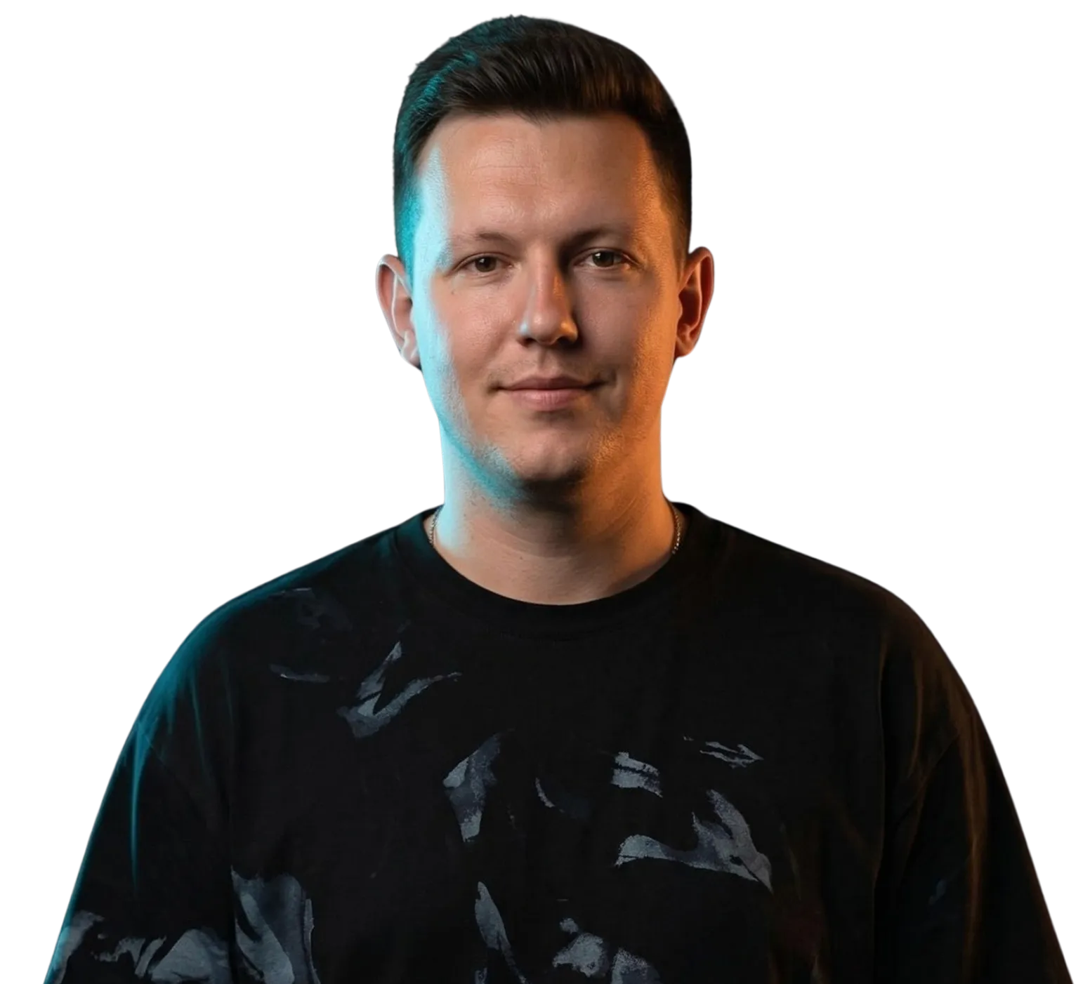 Portrait of a man with short dark hair wearing a black patterned shirt, smiling slightly.