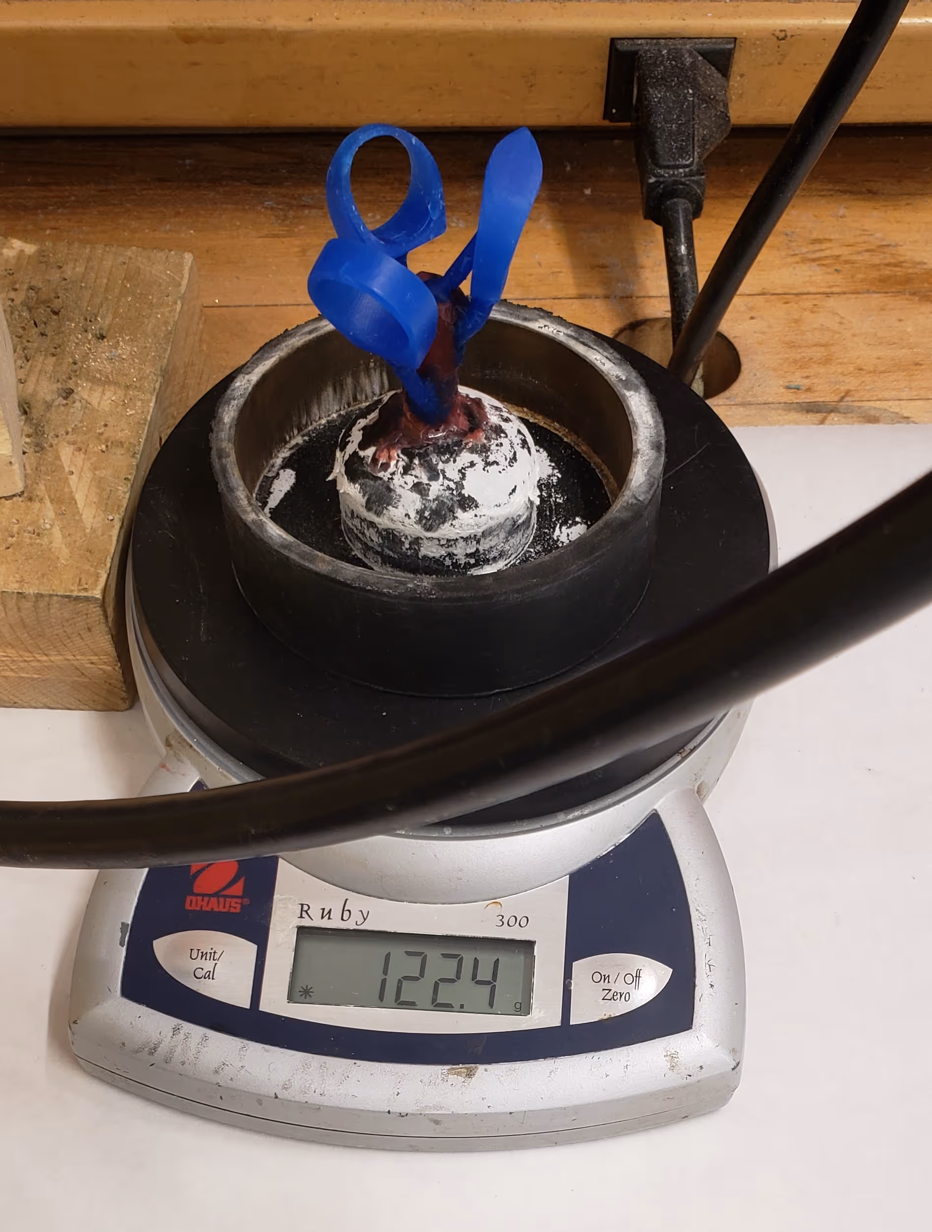 Image of wax tree with rings on its rubber stand being weighed for casting calculations.