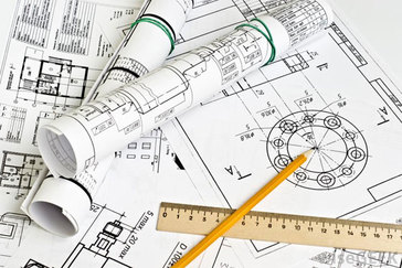 Architectural blueprints and technical drawings spread on a table with rolled plans, a wooden ruler, and a yellow pencil pointing at a circular diagram.