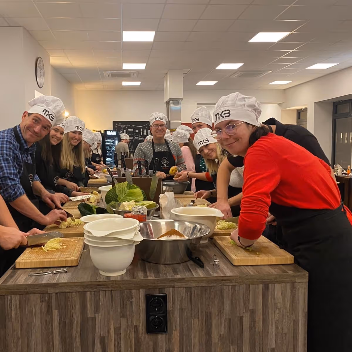 Team mit Kochmütze und Schürze bereitet Essen zu