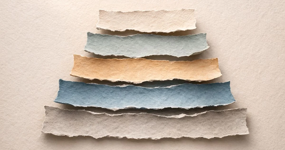 Minimalist torn-paper collage on a warm cream textured background showing five horizontal paper layers stacked upward in muted grey, blue, sand, and pale tones, each slightly offset with soft shadows, symbolising a structured coaching framework built on layered foundations leading to performance and growth.