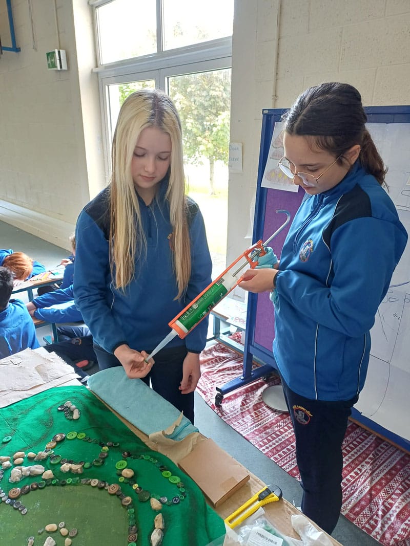 two girls gluing artwork together