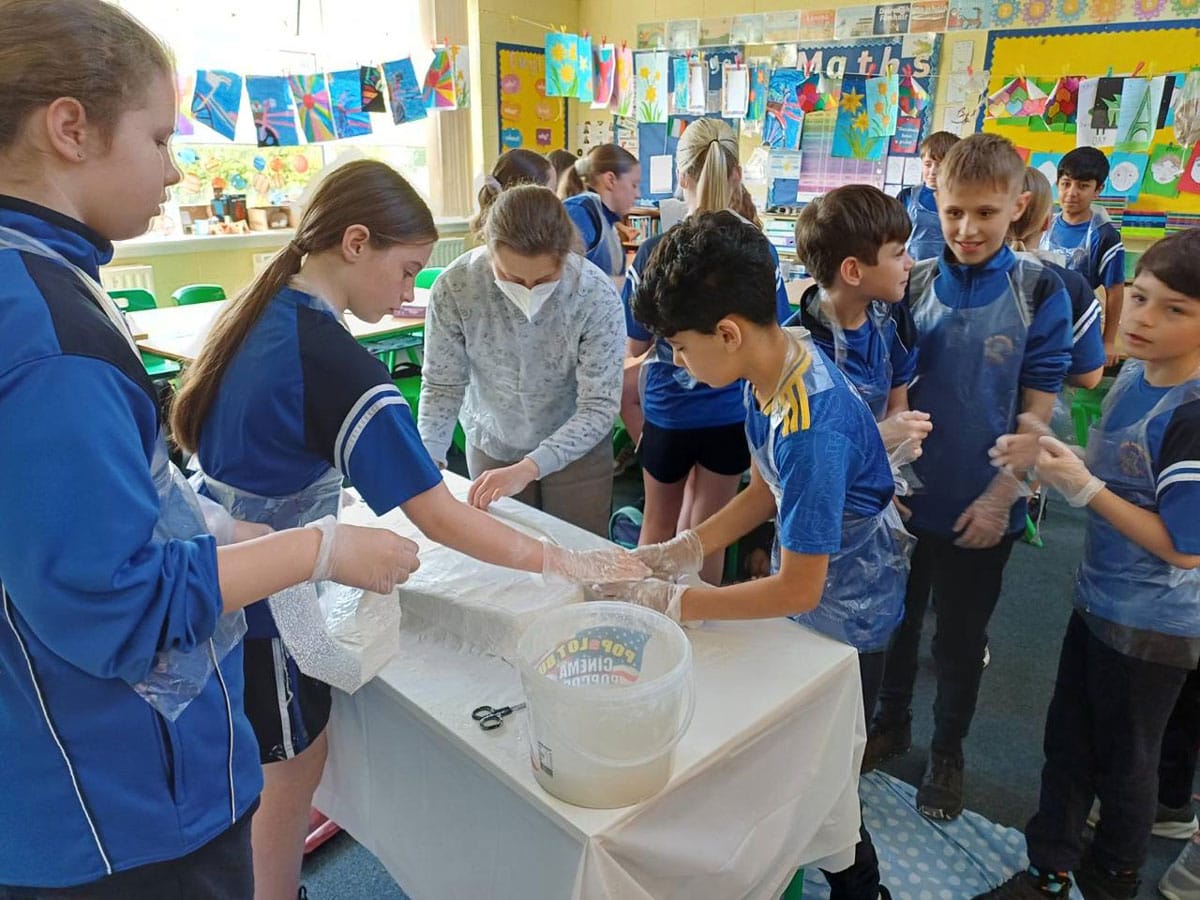 School children busy mixing plaster under artist instruction