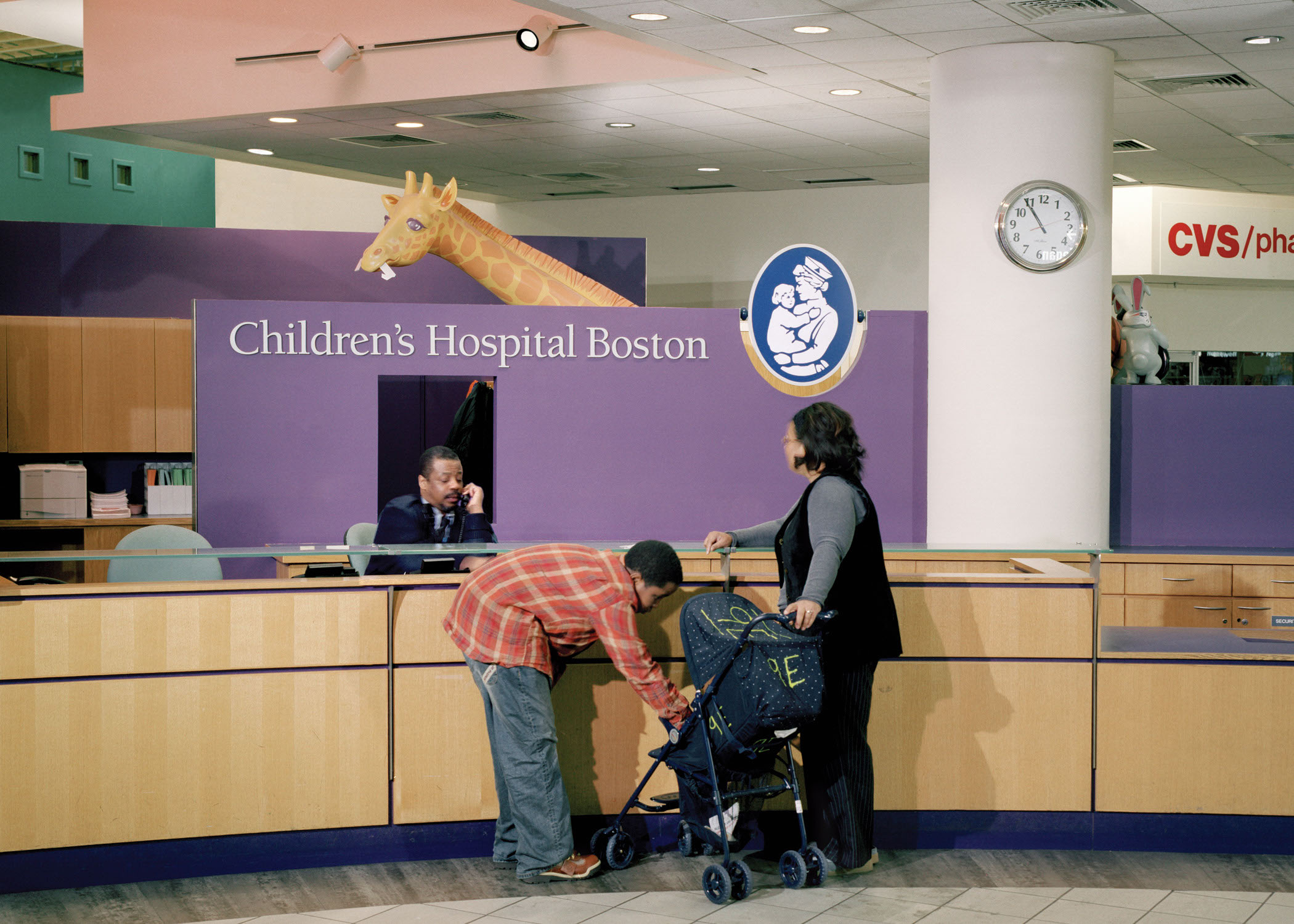 Children's Hospital Boston interior floor-standing identification signage behind reception desk with dimensional lettering and vertical monitor, designed by Two Twelve