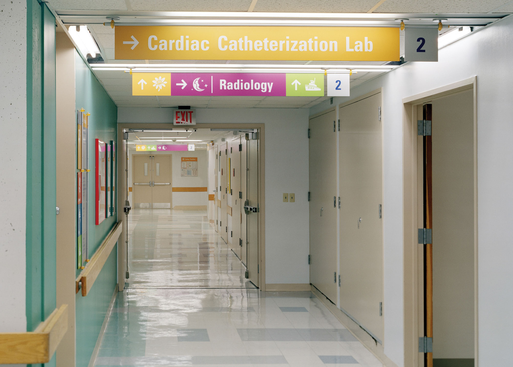 Children's Hospital Boston interior ceiling-mounted overhead identification and directional sign for Cardiac Lab with color-coded icons, designed by Two Twelve