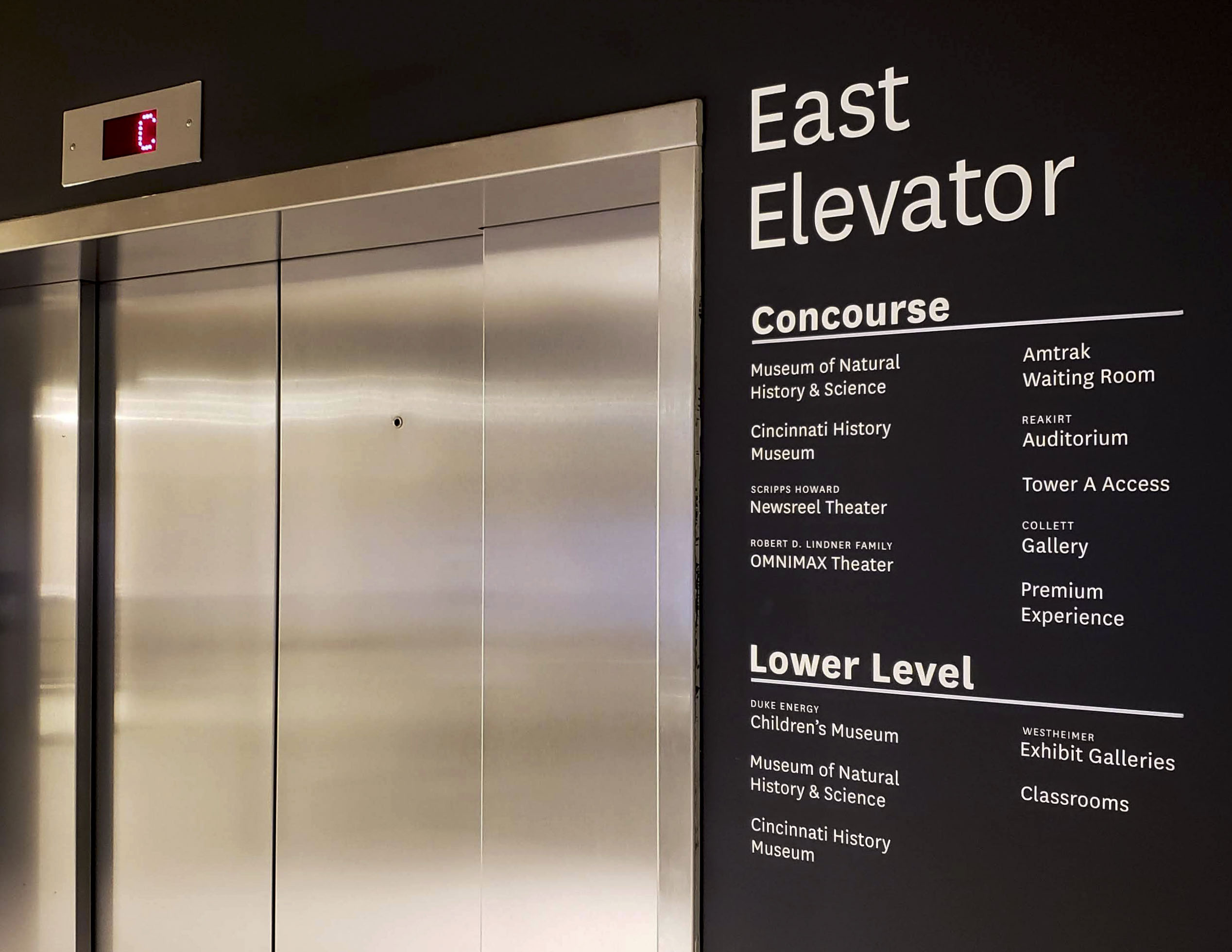 Cincinnati Museum Center interior identification and directory sign for East Elevator, Concourse, and Lower Level with white vinyl on black, designed by Two Twelve