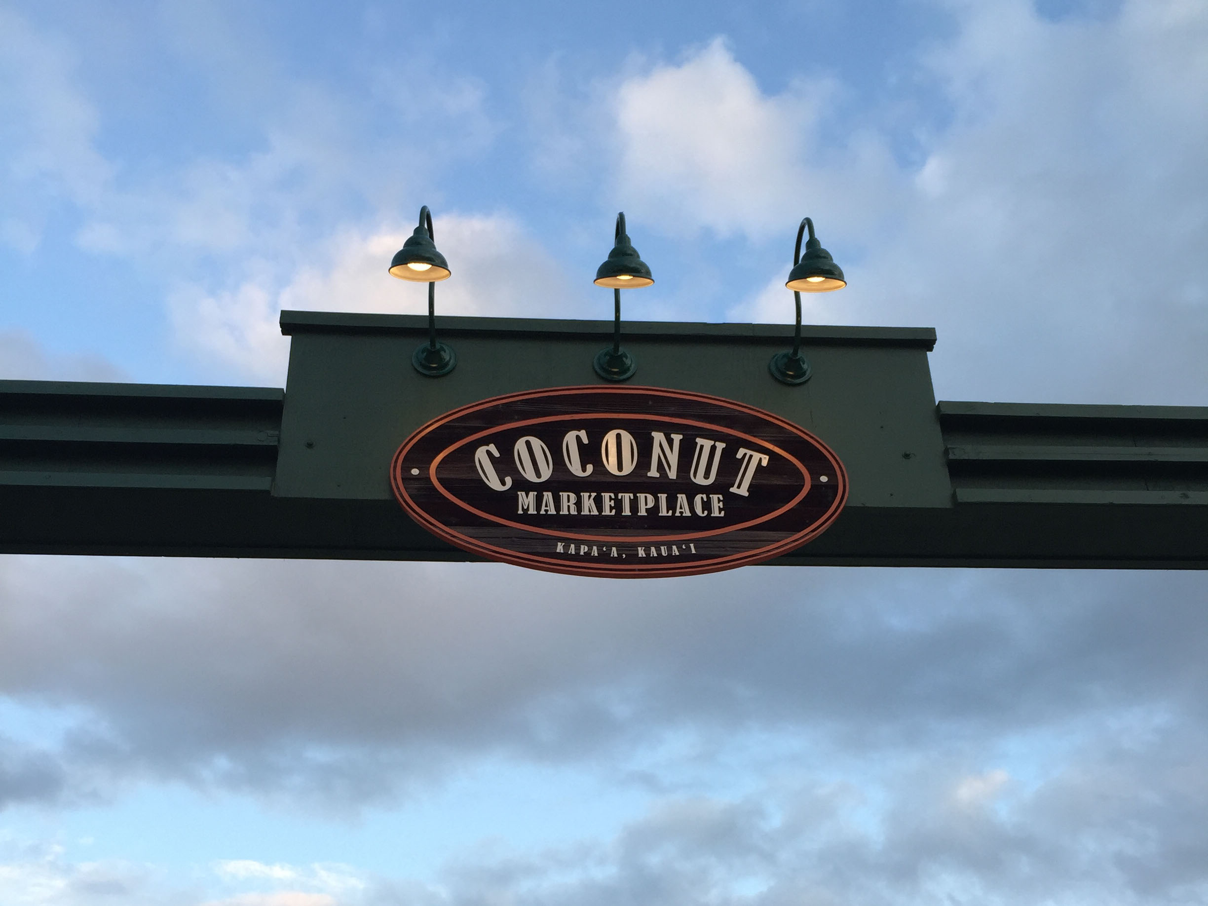 Coconut Marketplace exterior overhead gateway identification sign with wooden sign and vinyl text, designed by Two Twelve