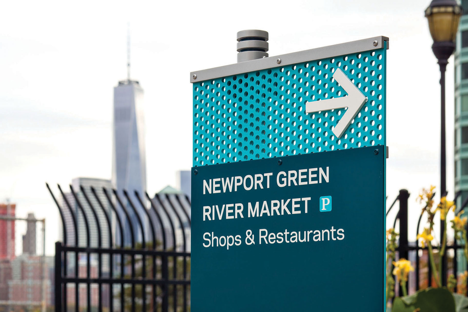 Community of Newport exterior post-mounted directional sign for River Market with blue perforated material, designed by Two Twelve