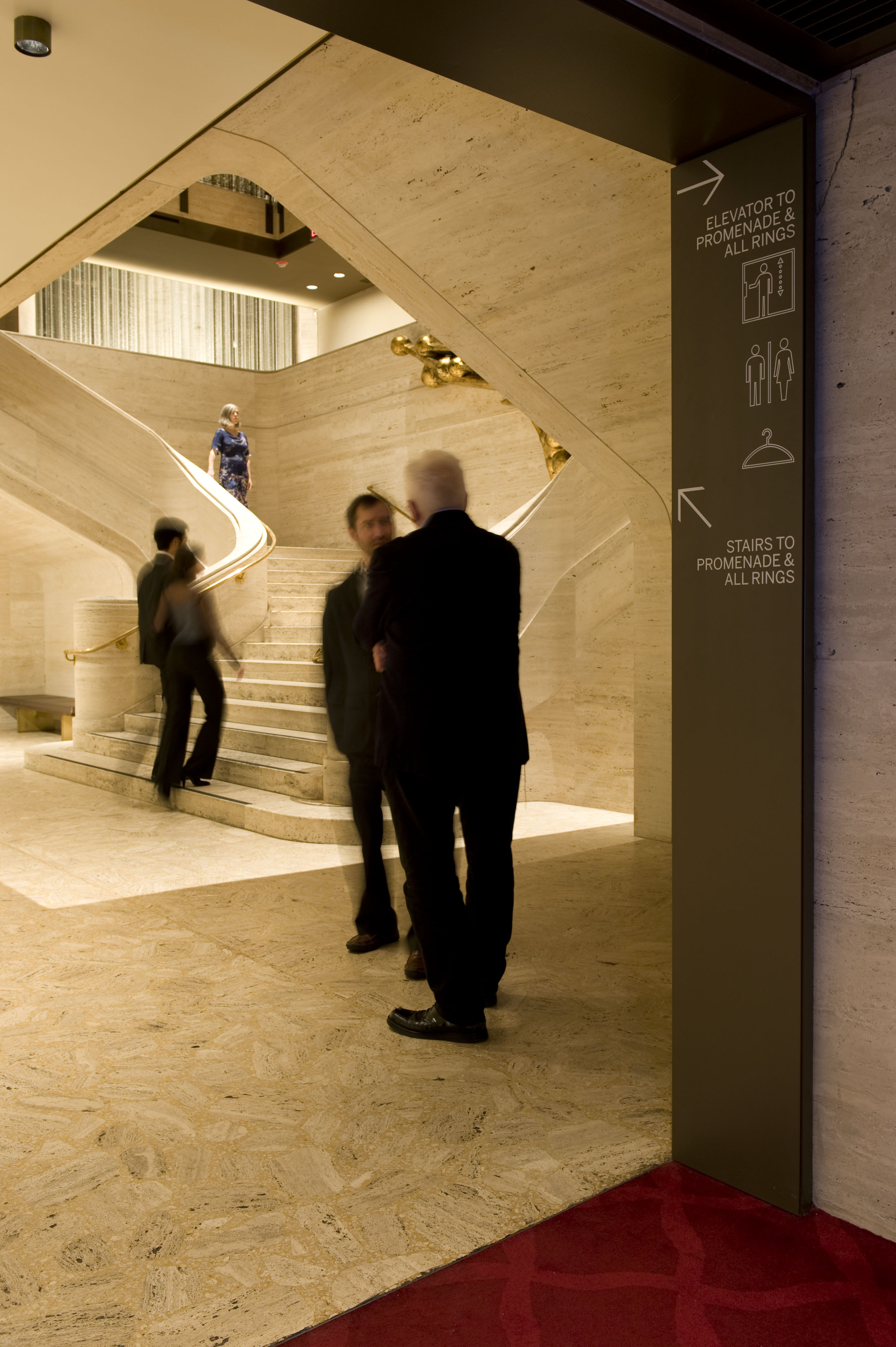 David H. Koch Theater at Lincoln Center interior directional sign with white vinyl text on black panel mounted to stone, designed by Two Twelve