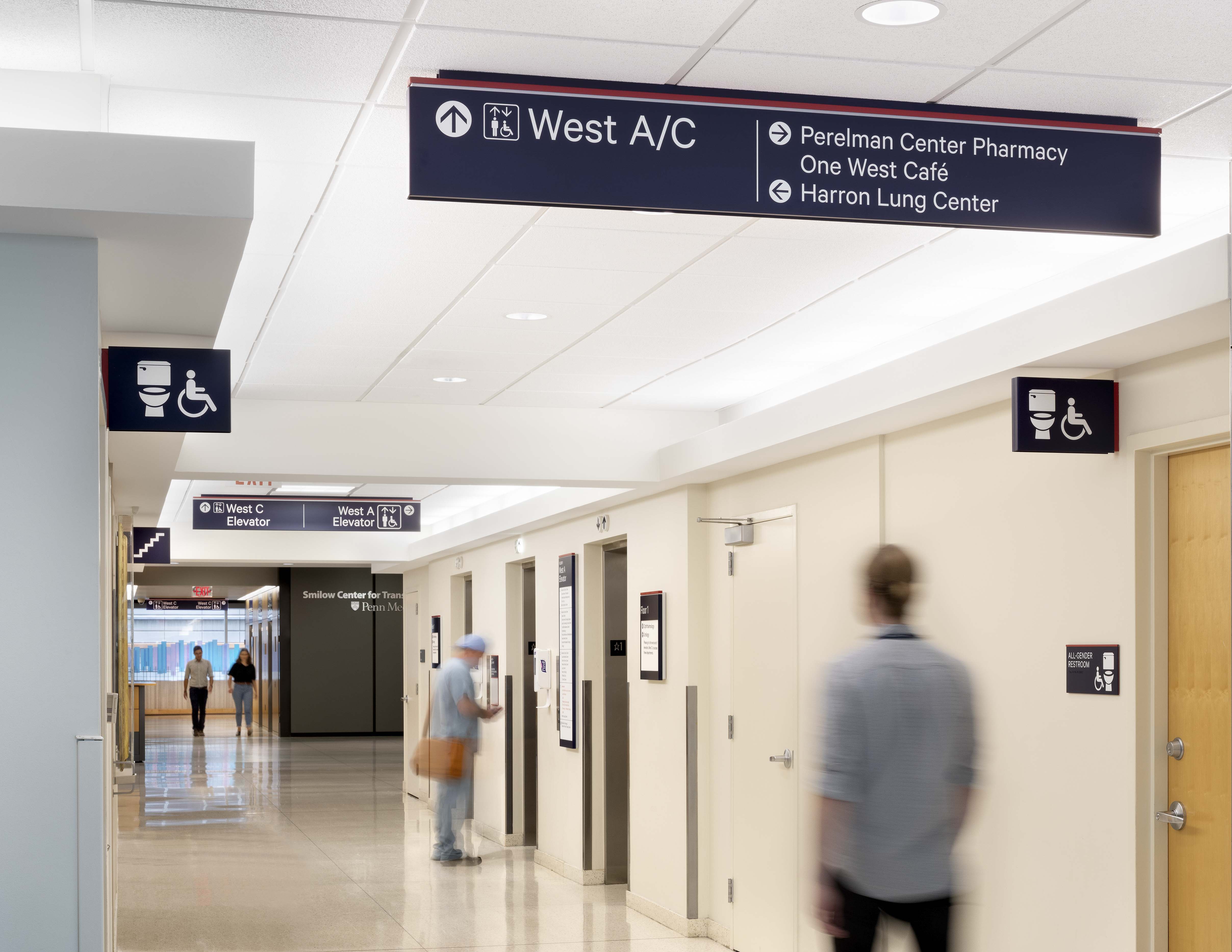 Penn Medicine overhead directional signage with connector identification and flag-mounted restroom signs, designed by Two Twelve
