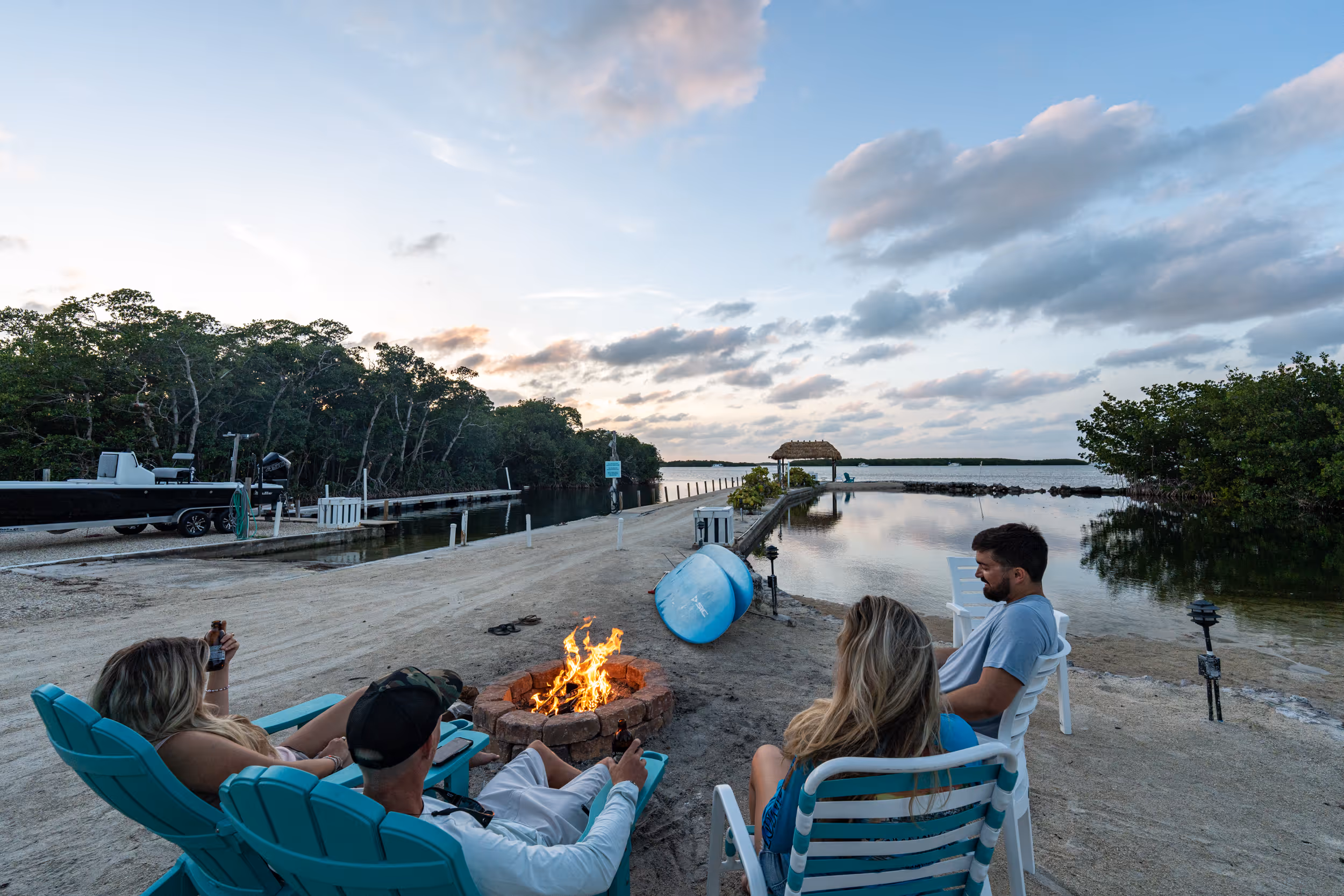 A couple sits on the Kon Tiki beach with a bonfire during the month of July.