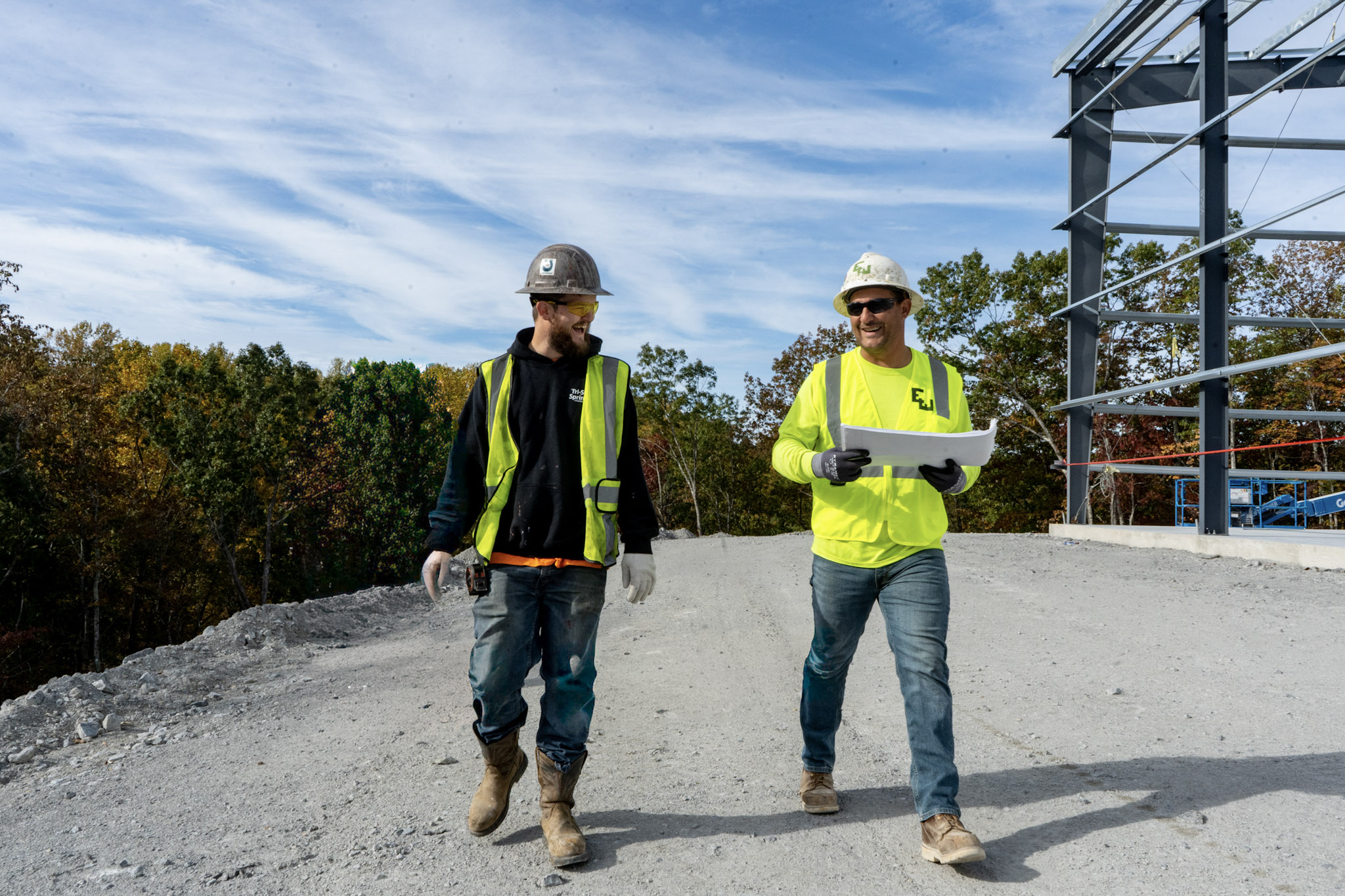 person wearing sunglasses and a hardhat smiles on an east and westbrook project site