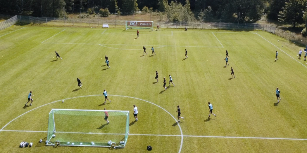 Flera fotbollsspelare spelar fotboll på en grön gräsplan.