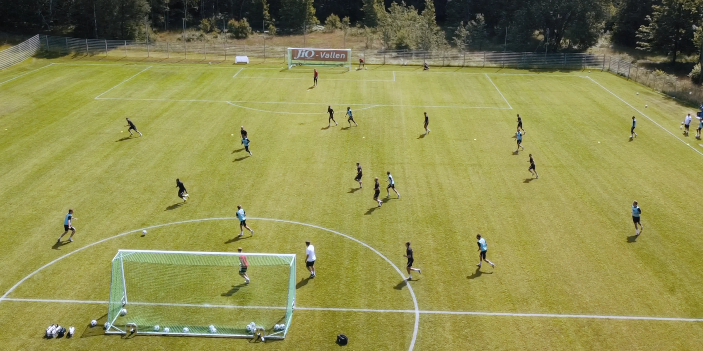 Flera fotbollsspelare spelar fotboll på en grön gräsplan.