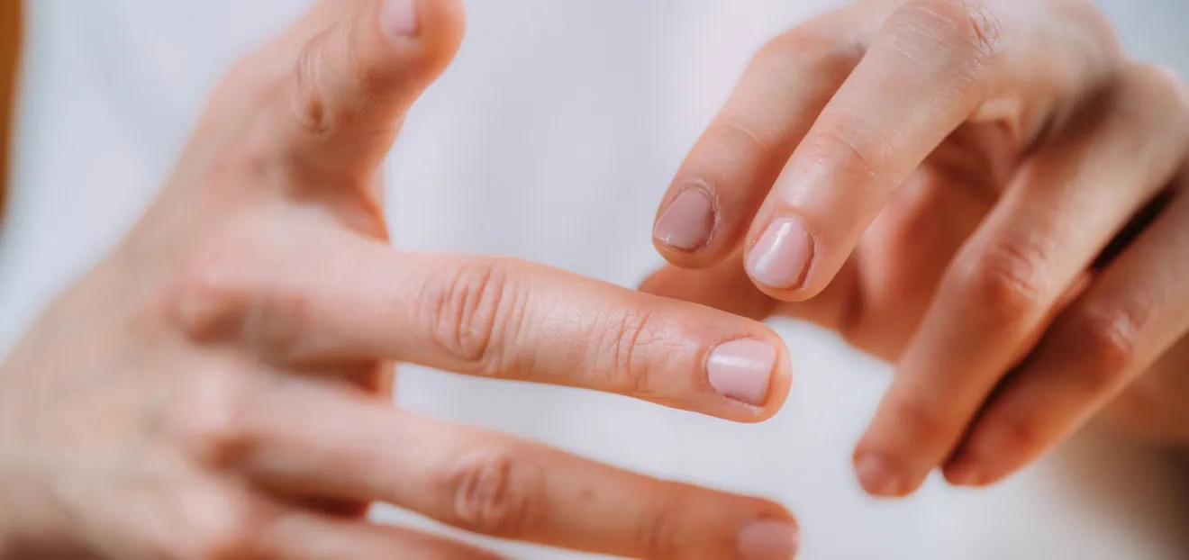 Frau berührt ihre Fingerspitzen – Kribbeln in den Fingerspitzen ist laut Studien ein häufiges Symptom beim Karpaltunnel Syndrom