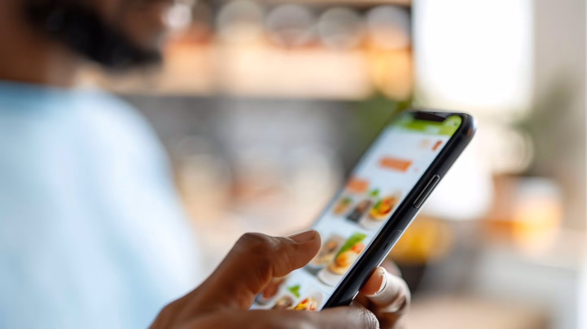 Person browsing a food delivery app on a smartphone, with meal options displayed on the screen.