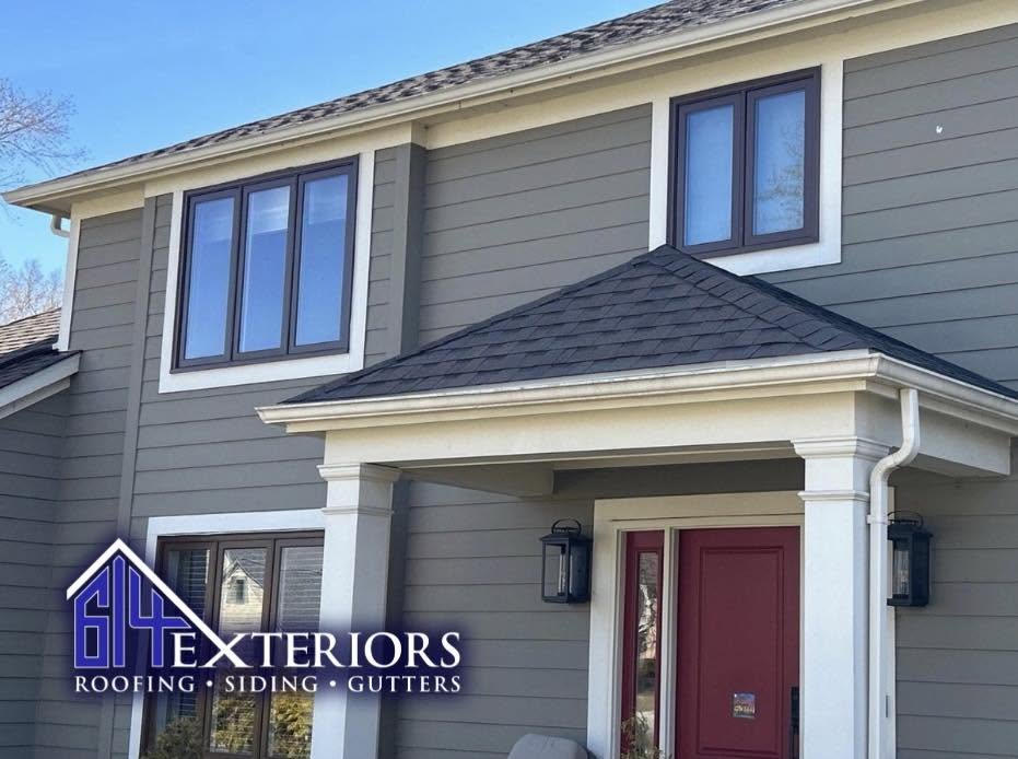 Two-story home with gray siding, white trim, black-framed windows, and a red front door.