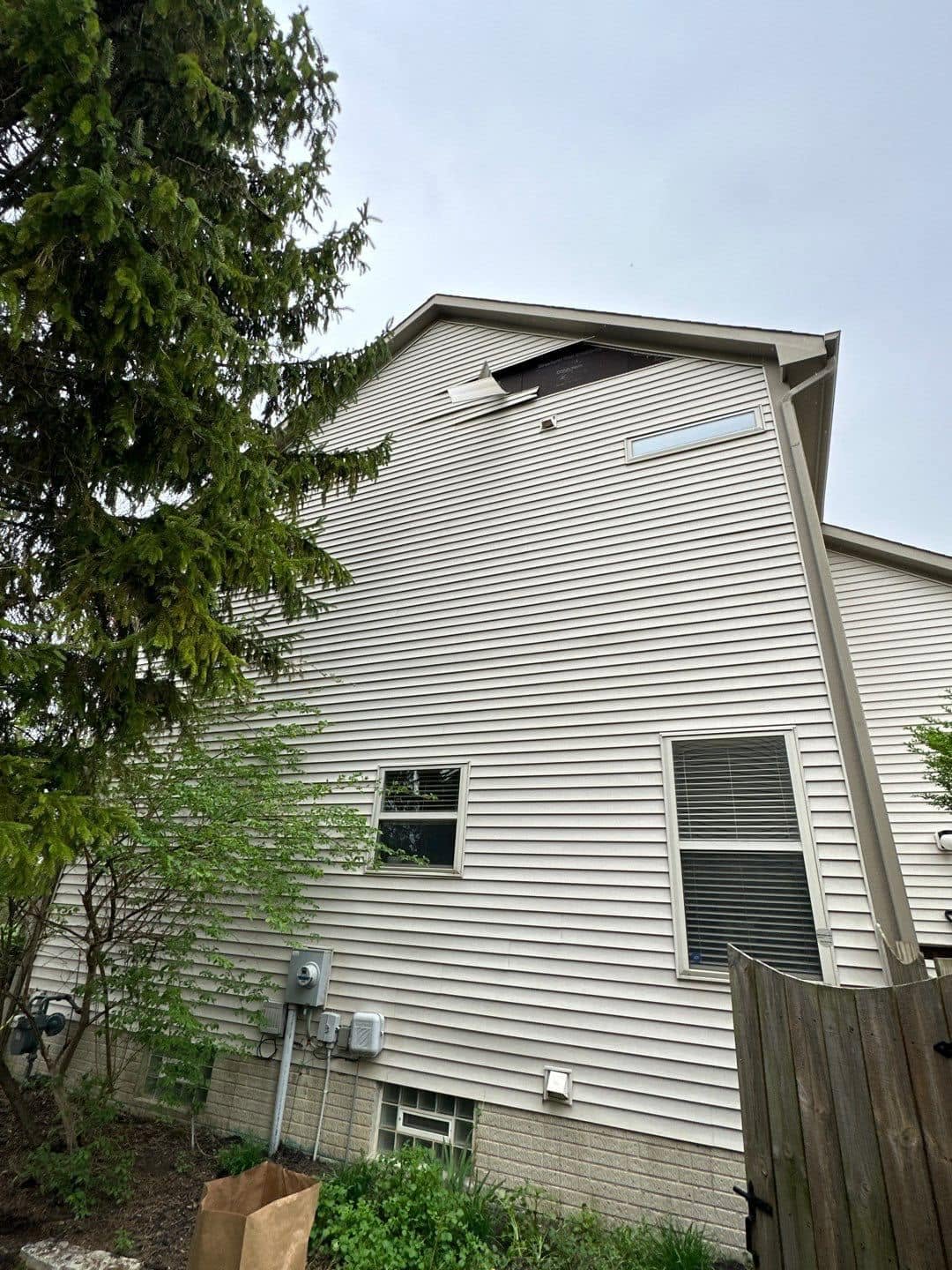 Damaged white vinyl siding near the roofline of an Ohio home