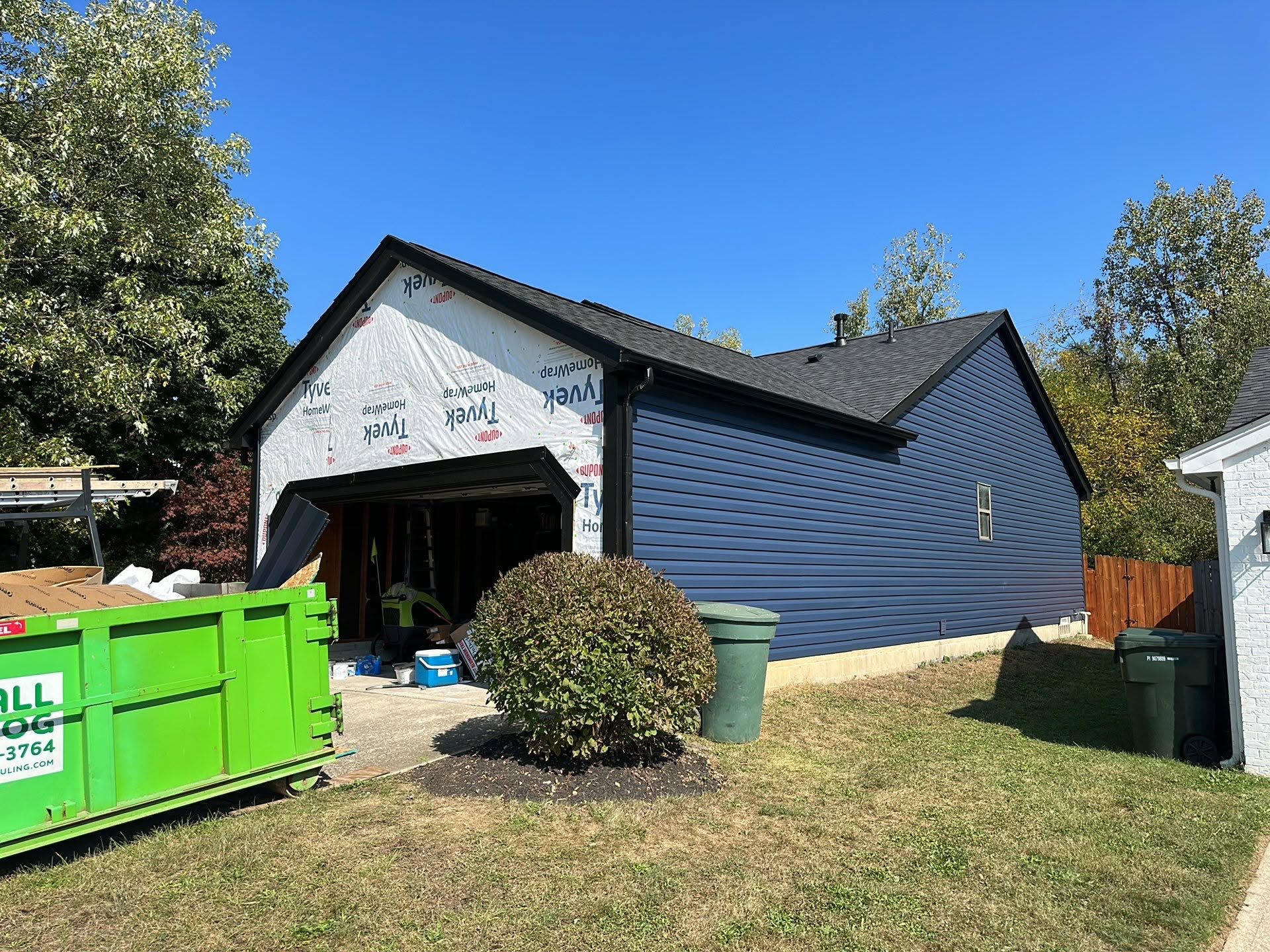 Blue vinyl siding installation in progress on a residential garage