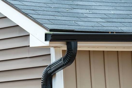 Black gutter and downspout system installed along a residential roofline