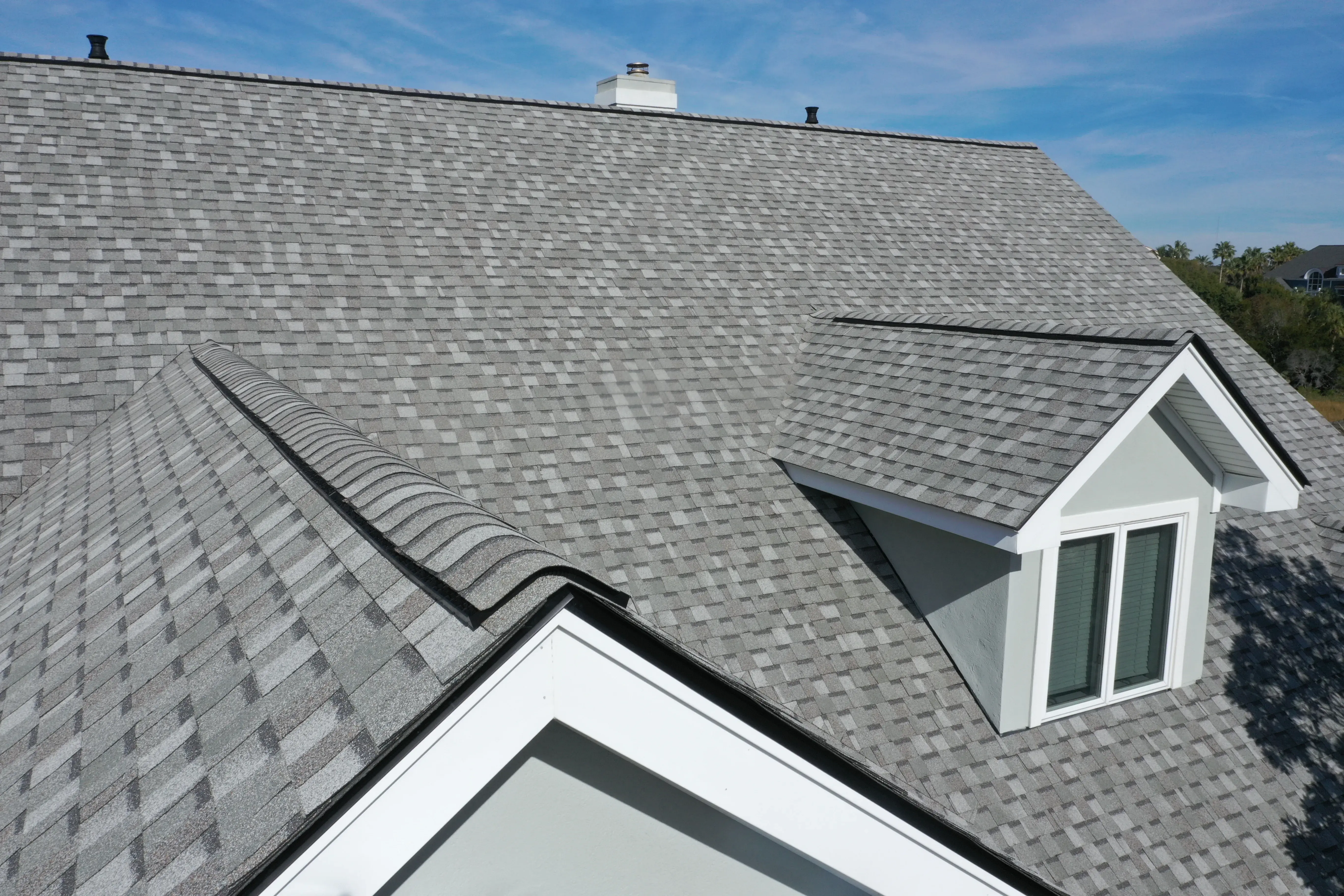 Gray architectural asphalt shingle roof with dormers on a residential home