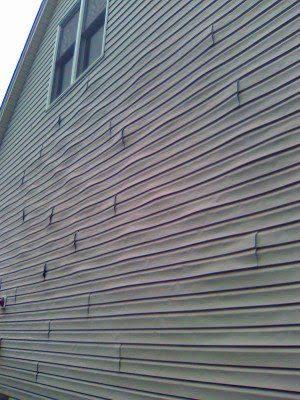 Severe vinyl siding warping and buckling across the side of a home