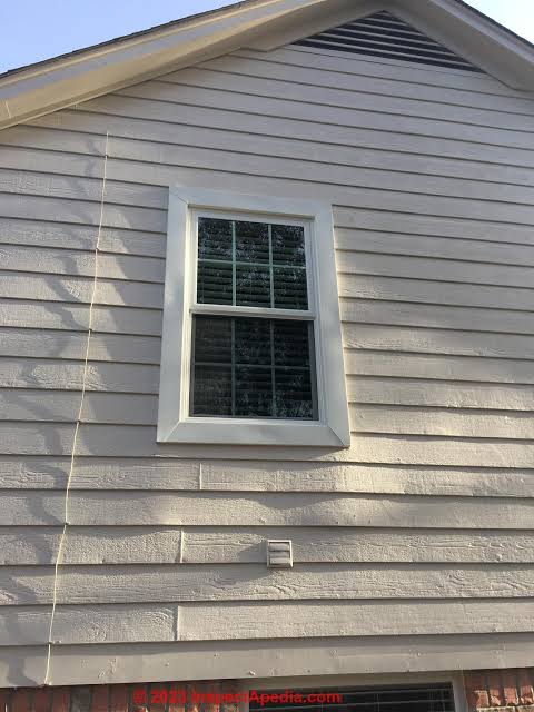 Warped and buckled vinyl siding around a window with visible heat-related distortion