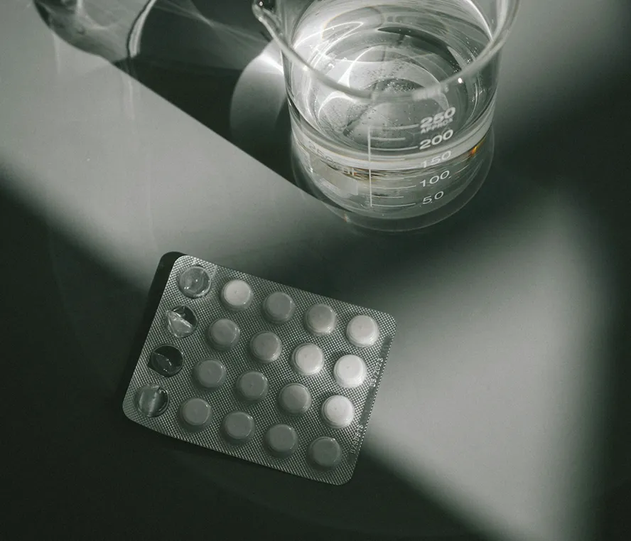 Image of pills and a beaker of water