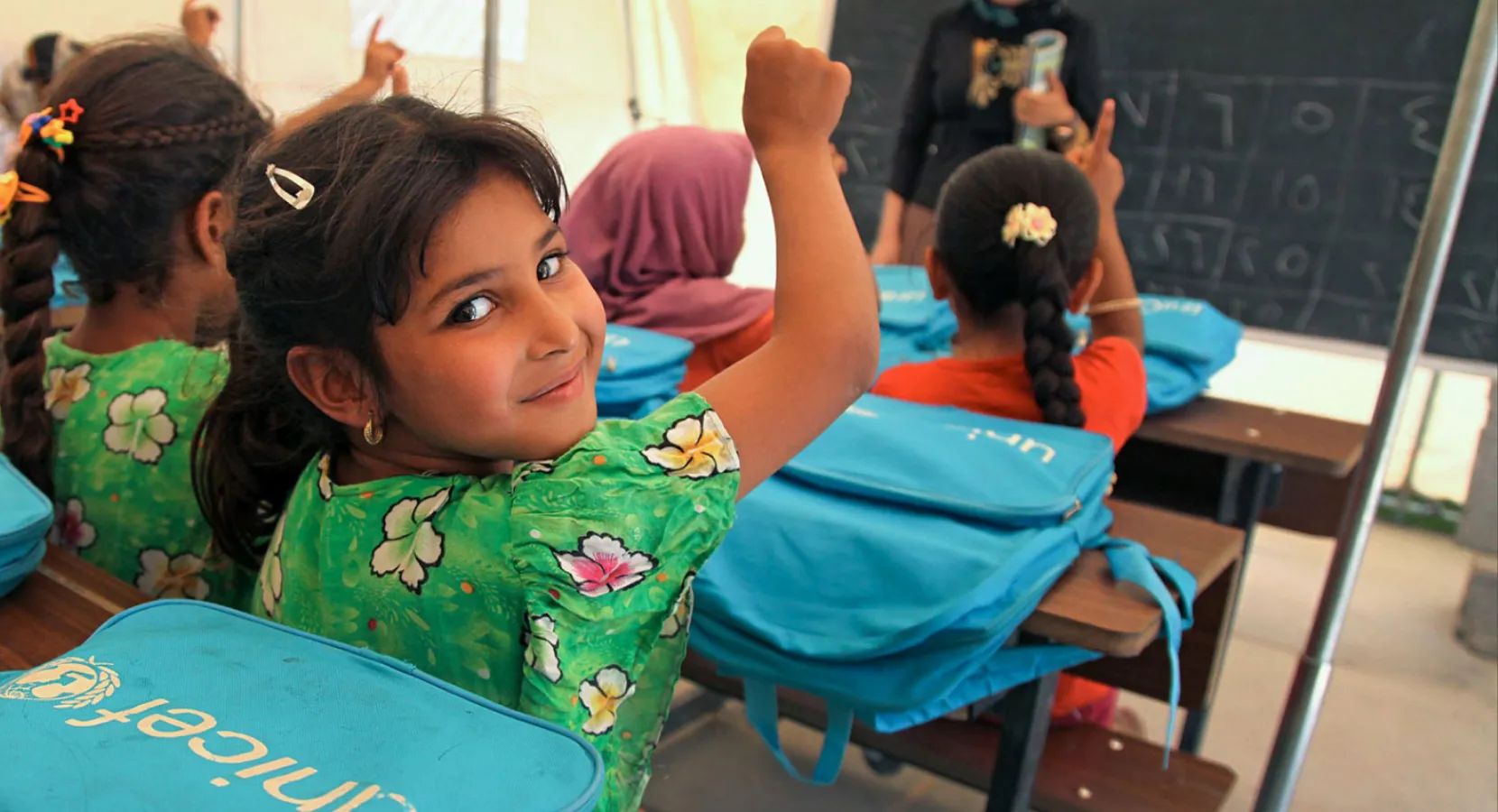Schoolgirl in class with UNICEF bag