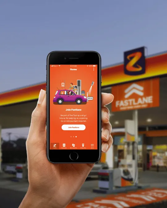 An image of a hand holding a phone with the Z Fastlane app open, in front of a Z Energy station