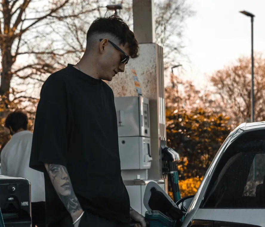 A hand holding a fuel pump filling up a car